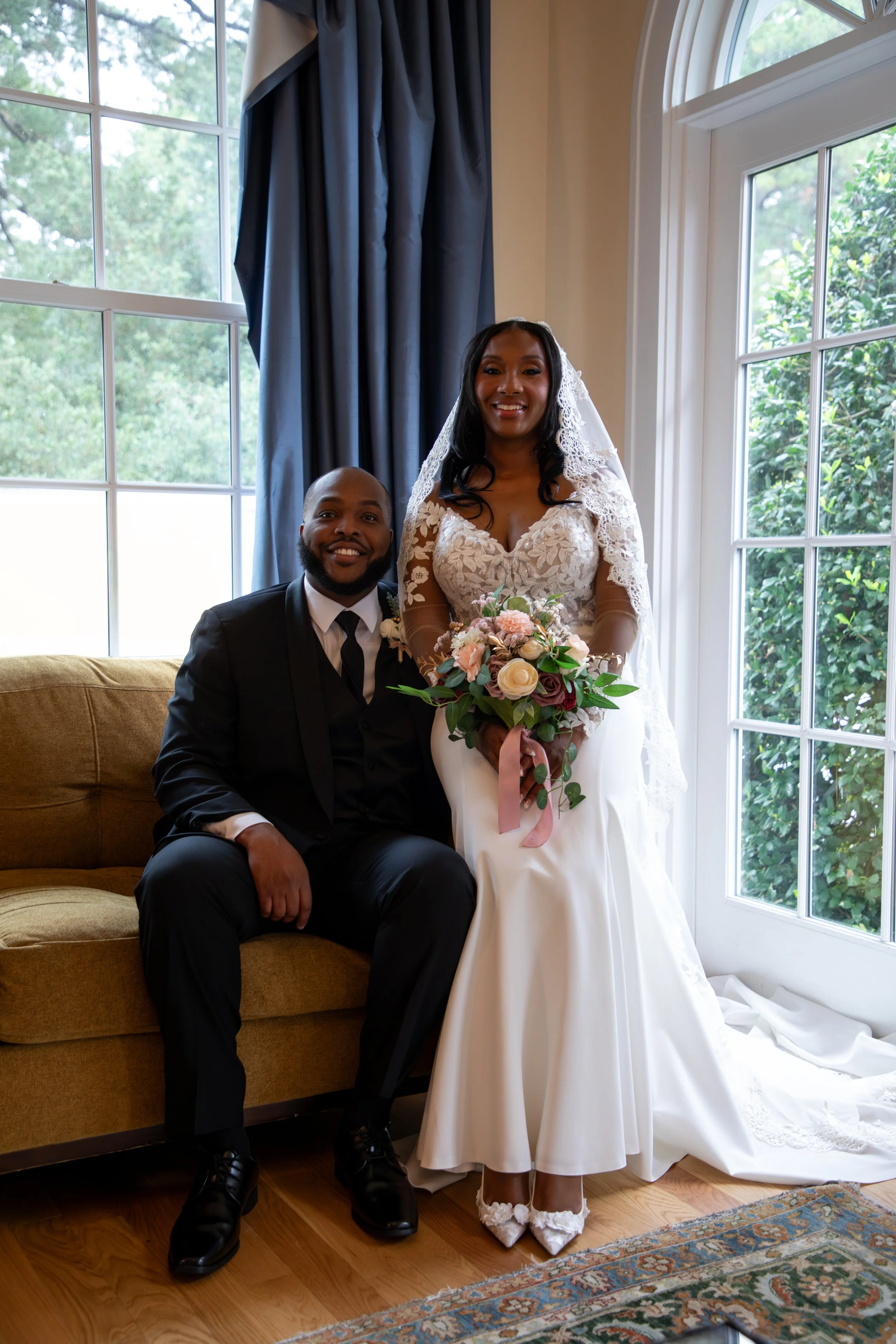 Photo & Video by Will Locke Wedding Photography at the Woman's Club of Portsmouth in Virginia. A bride and groom posing together indoors near large windows with greenery outside.