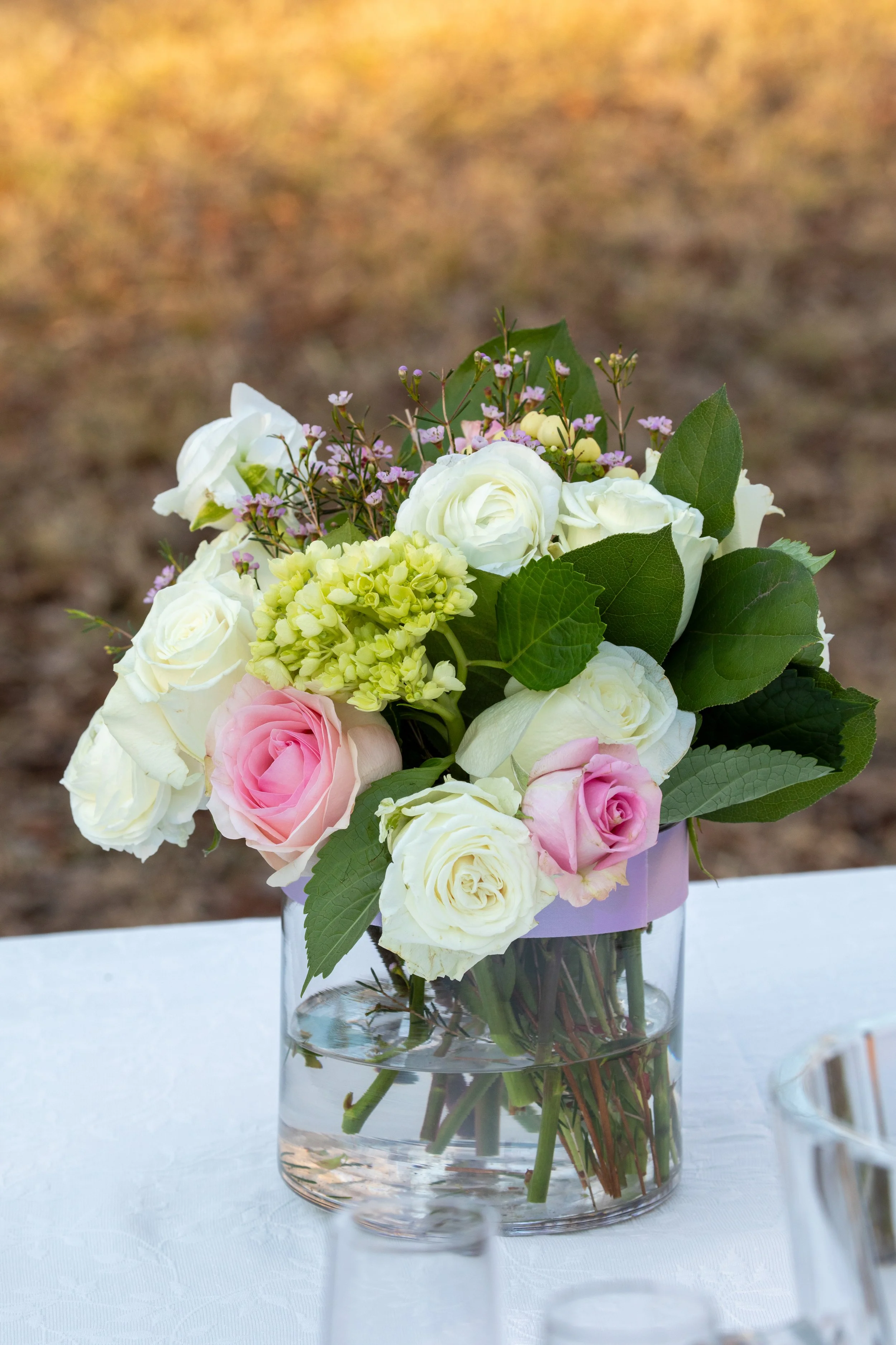 Engagement Photography by Will Locke near Richmond, VA in Montpelier. A flower arrangement sits on a white tablecloth outdoors in the winter with grass behind.