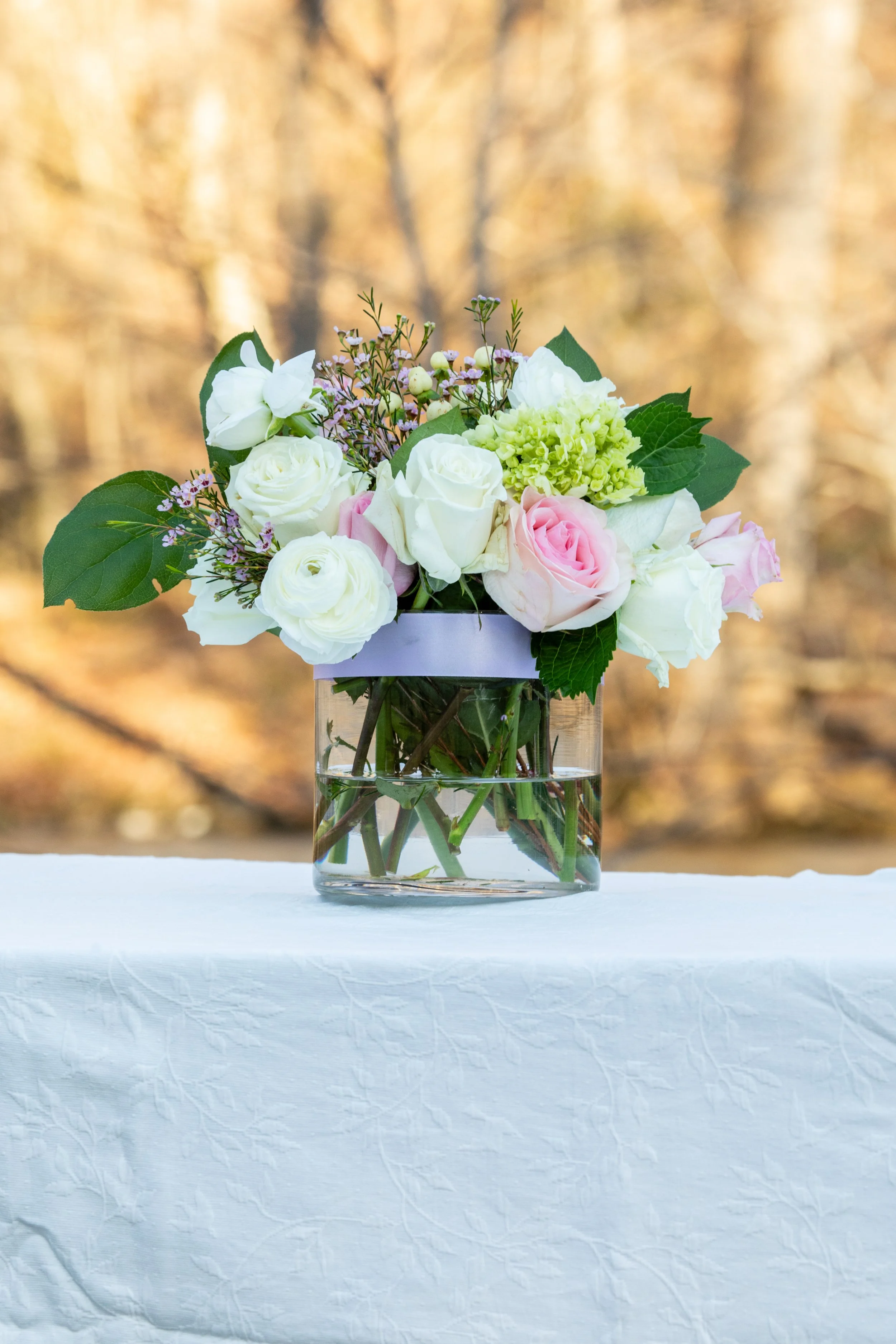 Engagement Photography by Will Locke near Richmond, VA in Montpelier. A flower arrangement sits on a white tablecloth outdoors in the winter with grass behind.