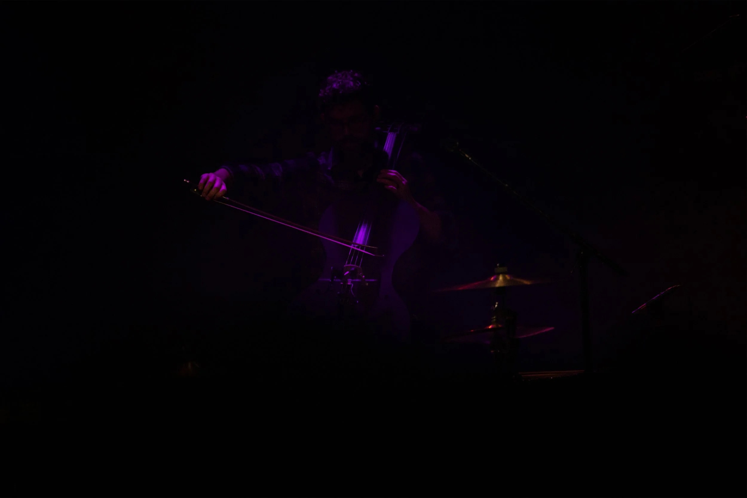 Concert Photography by Will Locke. Musician playing a cello with purple lighting in a dark setting.