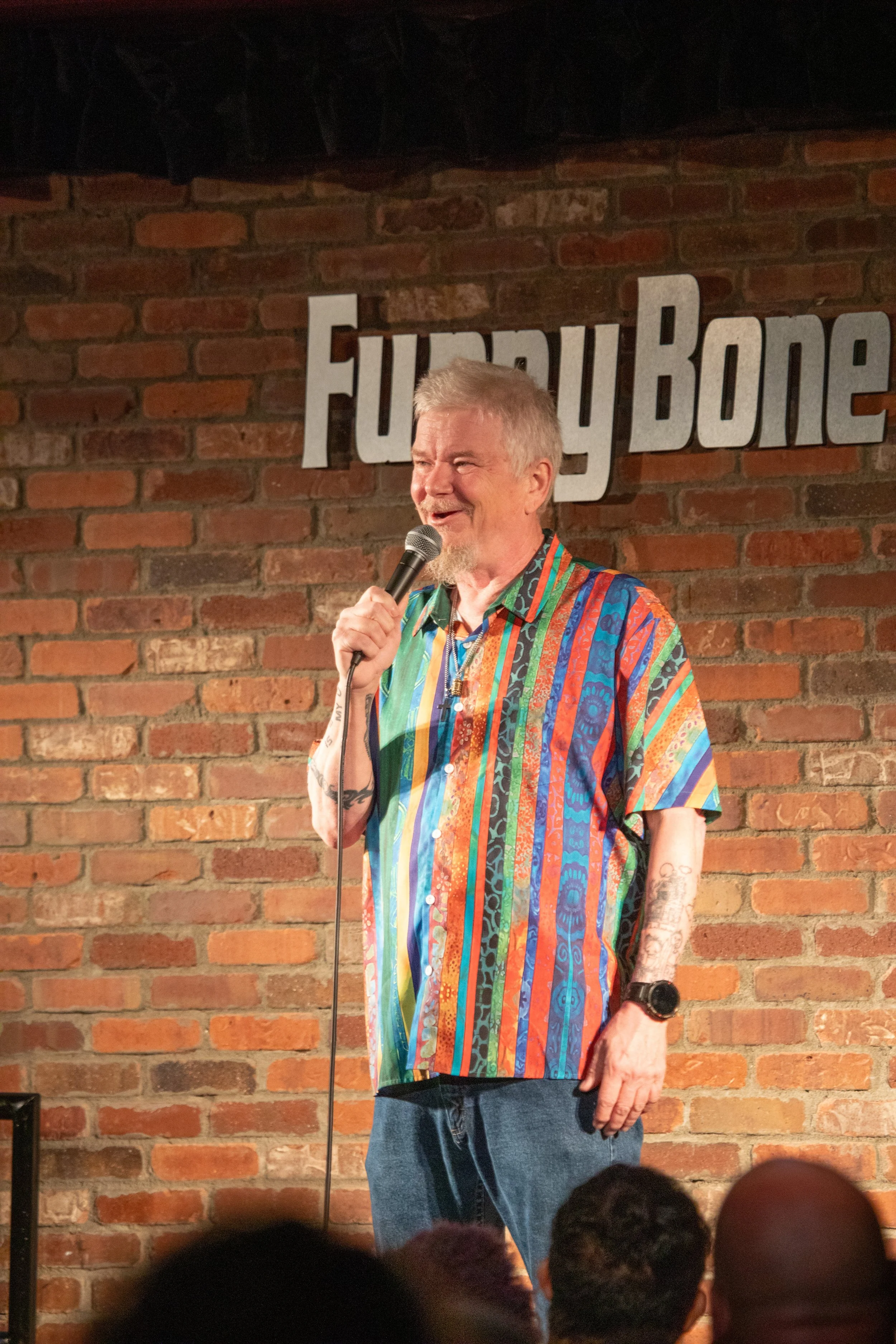 Comedy Photography by Will Locke in Norfolk, VA. Male comedian with gray hair talks into microphone on stage.