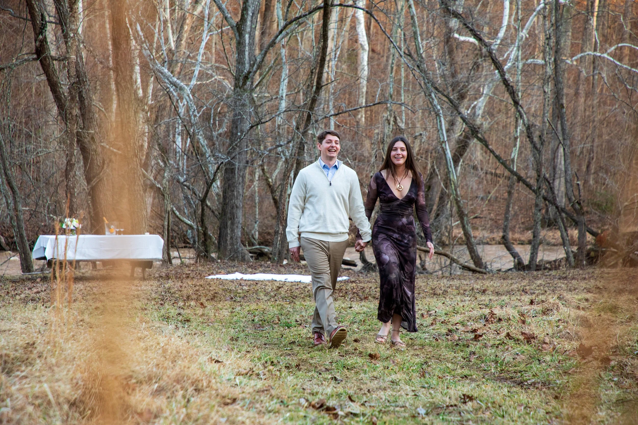 Engagement Photography by Will Locke near Richmond, VA in Montpelier. A couple walks while holding hands, with trees and a river in the background.