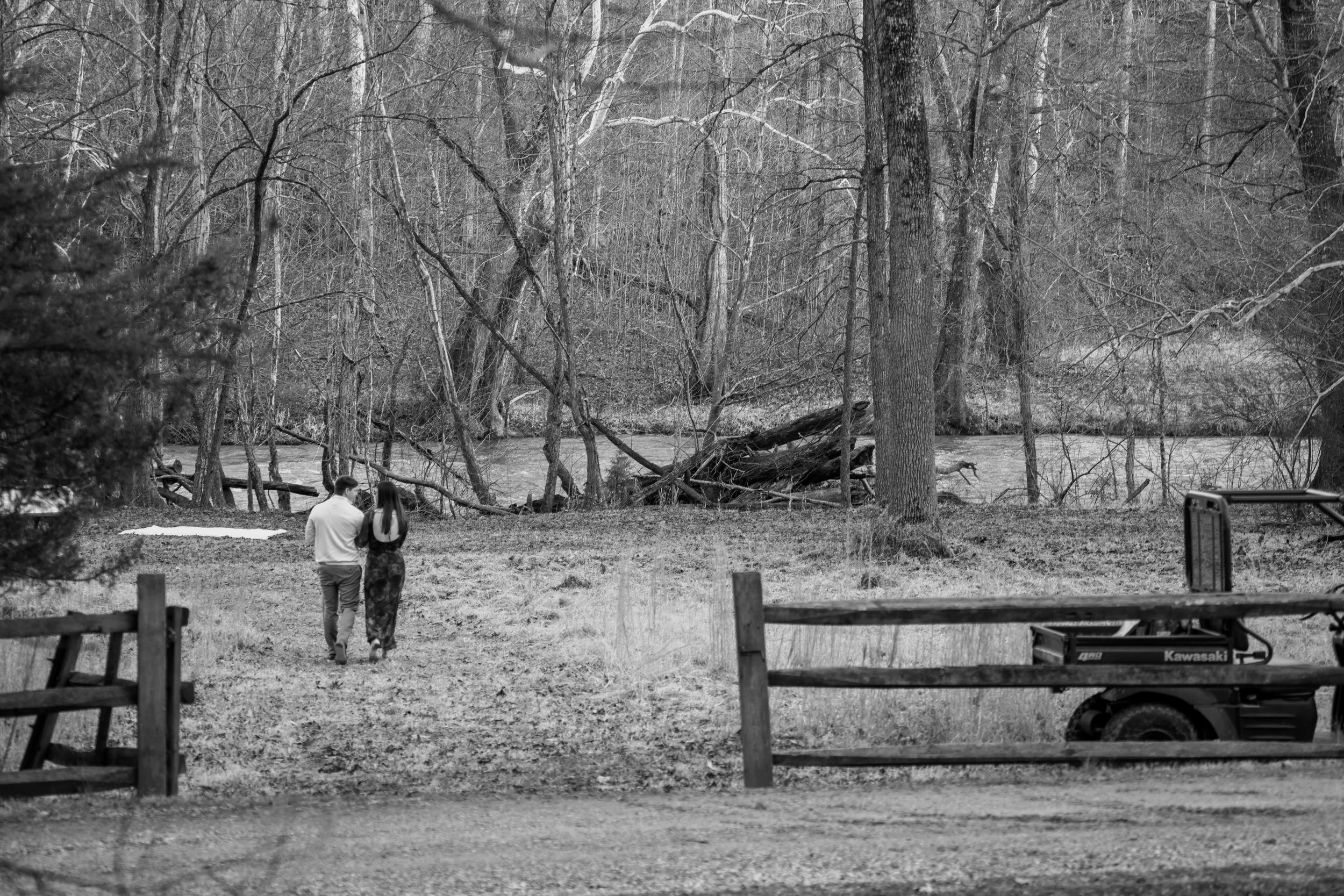 Engagement Photography by Will Locke near Richmond, VA in Montpelier. A couple walks on a white cloth on the ground near a wooded area with a stream on a fall day, with a Kawasaki utility vehicle.