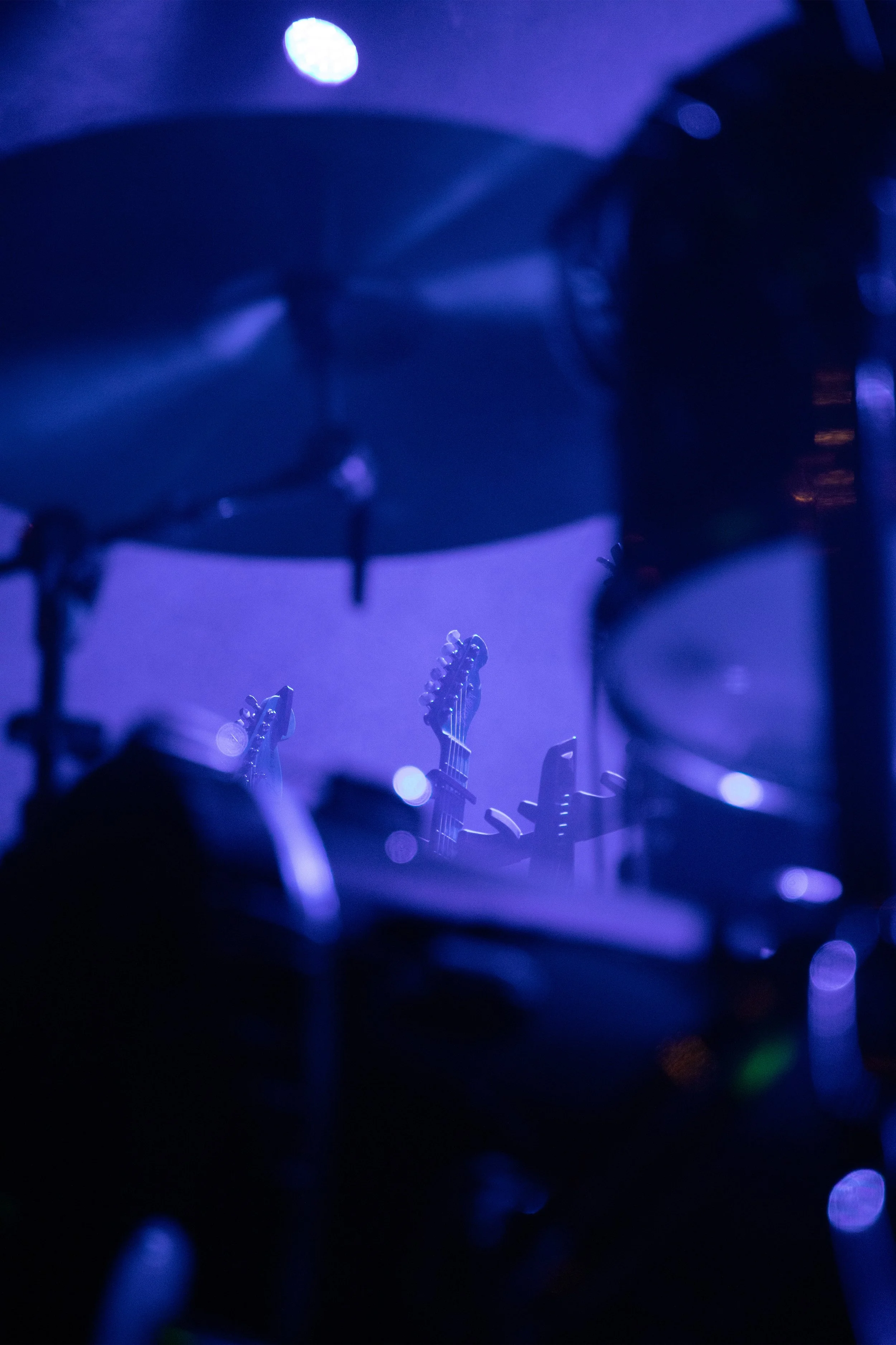 Concert Photography by Will Locke. A stage with blue lighting showing drums and guitars in the background.