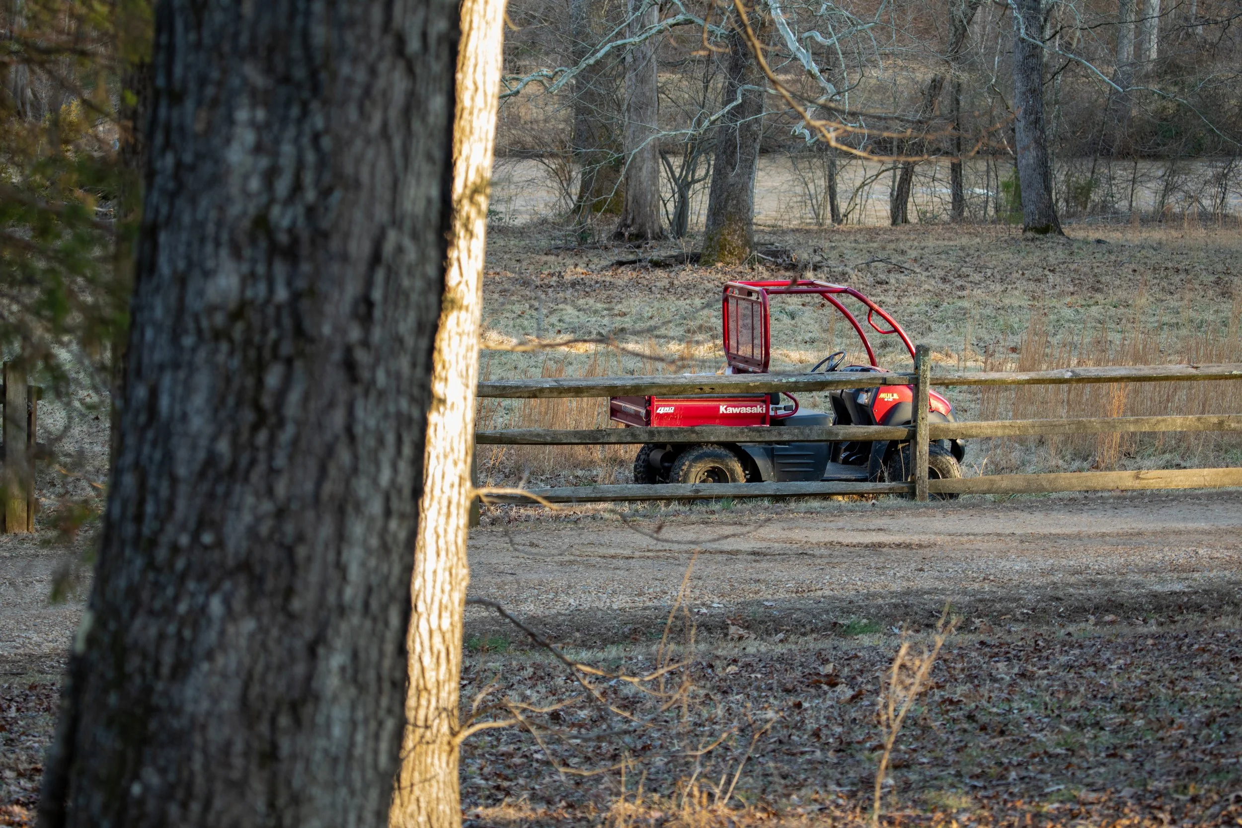 Engagement Photography by Will Locke near Richmond, VA in Montpelier. A Kawasaki Mule utility vehicle sits by a wood fence in front of a flowing river.