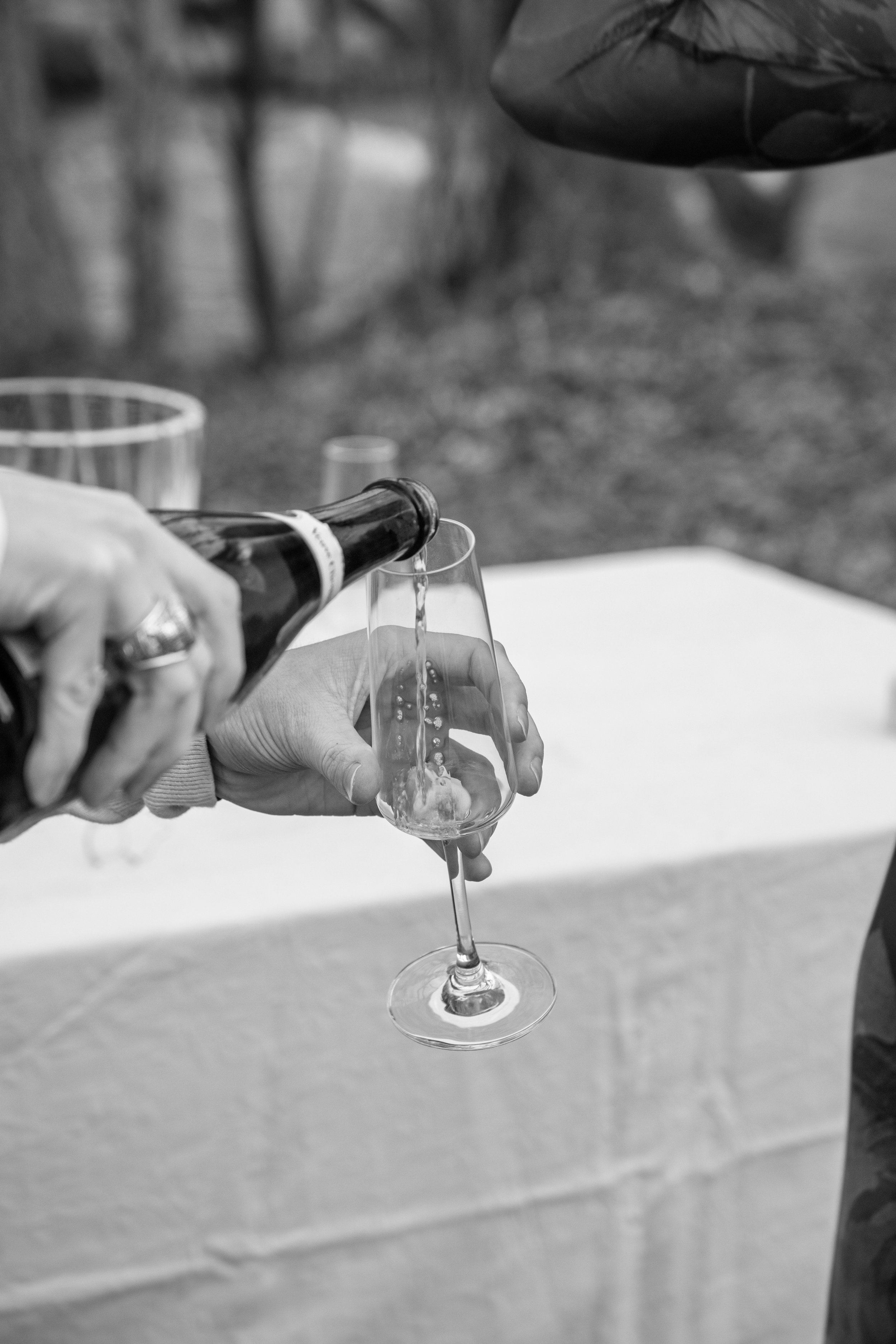 Engagement Photography by Will Locke near Richmond, VA in Montpelier. A glass of champagne is being poured, with a table and a bottle of champagne in the background.