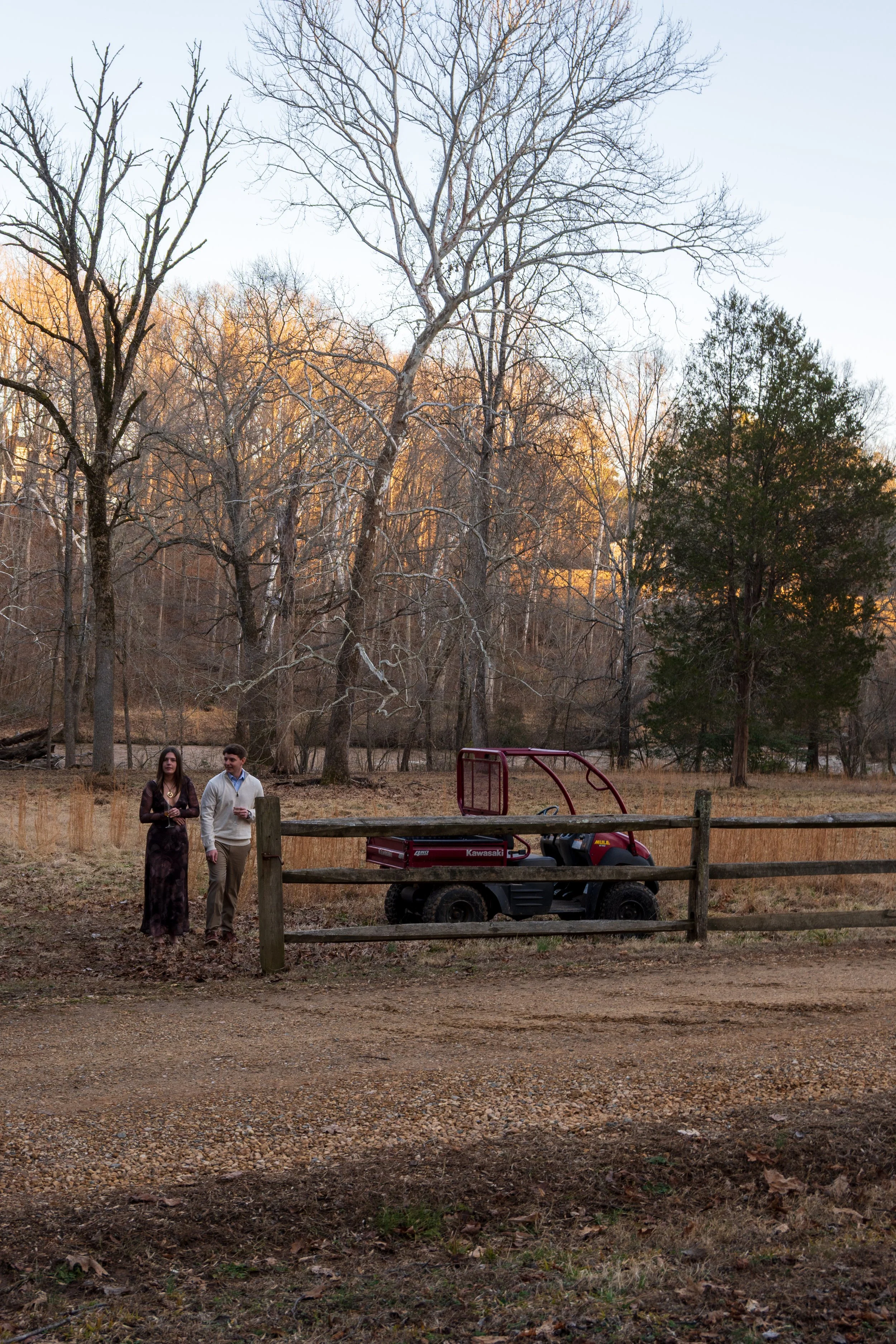 Engagement Photography by Will Locke near Richmond, VA in Montpelier. A newly engaged couple stands near a wood fence and red Kawasaki Mule utility vehicle.