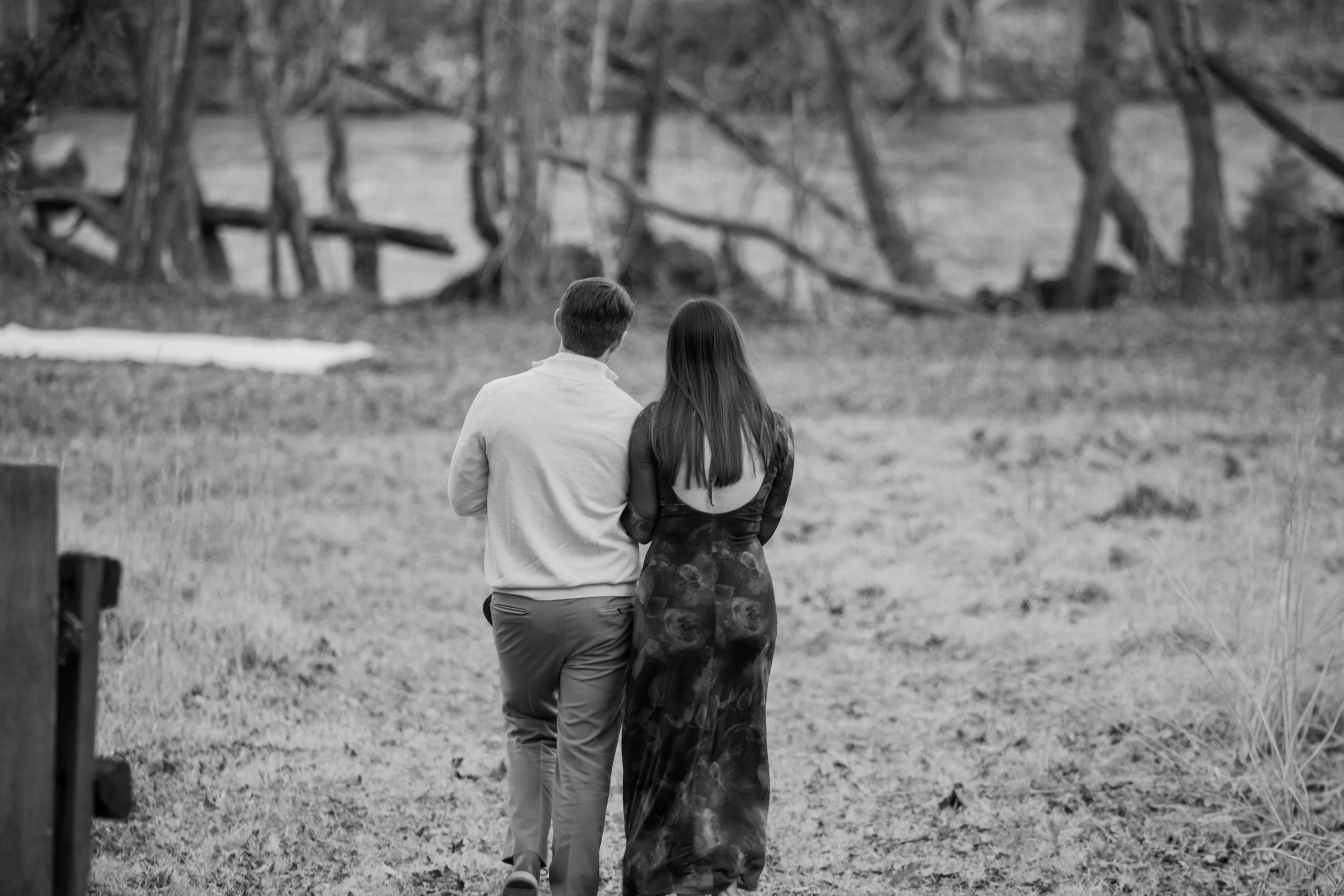 Engagement Photography by Will Locke near Richmond, VA in Montpelier. A couple walks to a white cloth on the ground near a wooded area with a stream on a fall day.