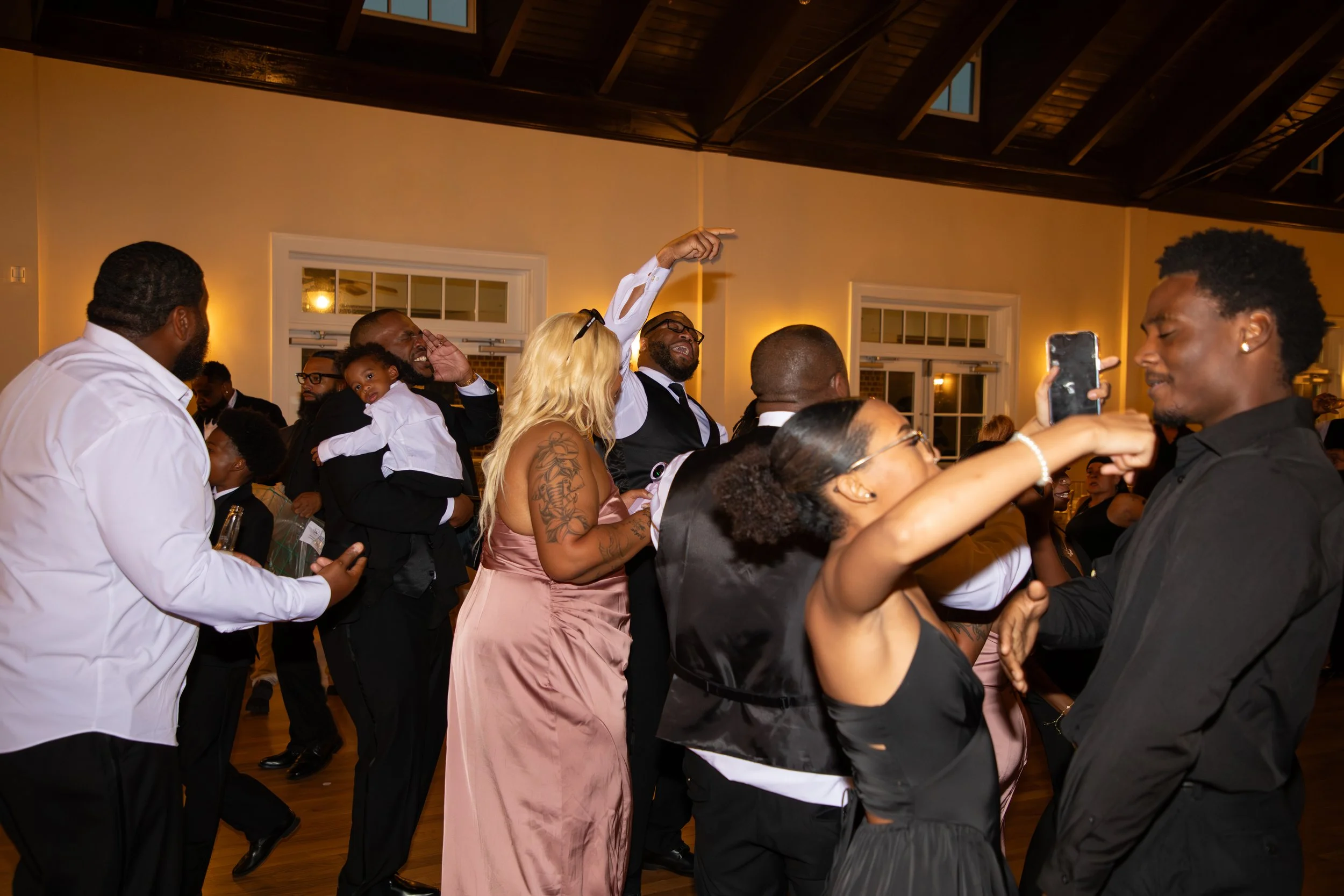 Wedding Photography by Will Locke. People dancing and having fun at a celebration in a decorated indoor venue.
