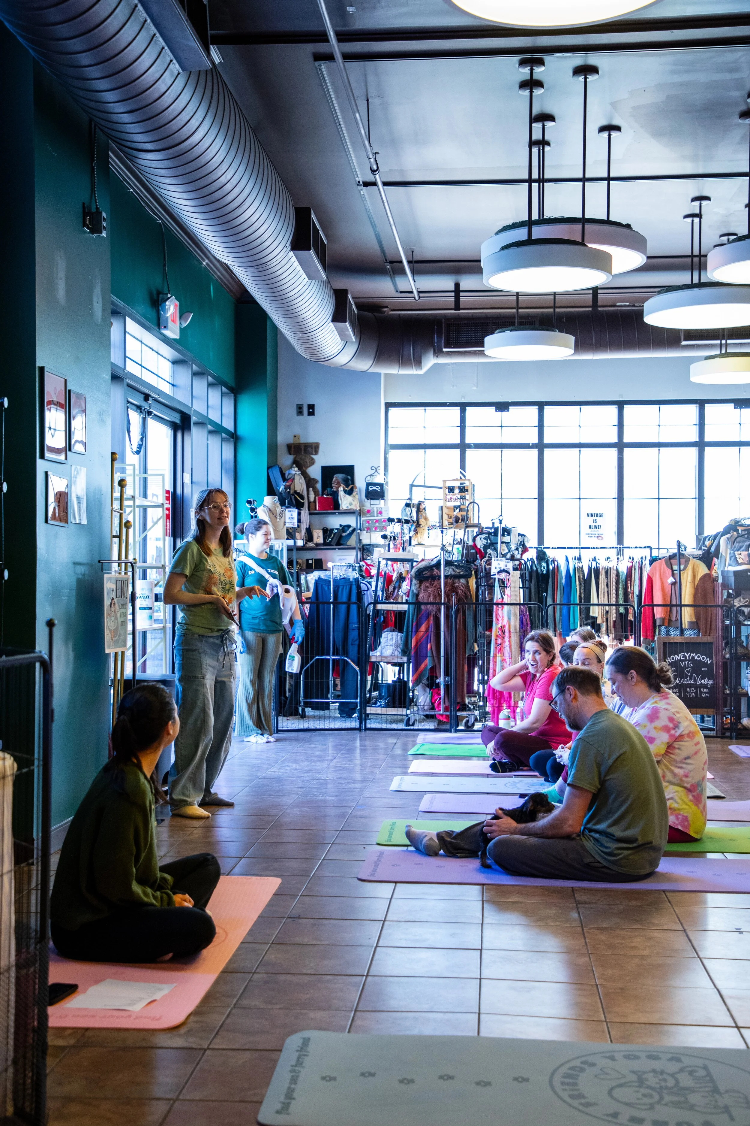 Marketing and Event Photography by Will Locke. People participating in a yoga class inside a retail store, sitting on yoga mats facing a woman who appears to be instructing.