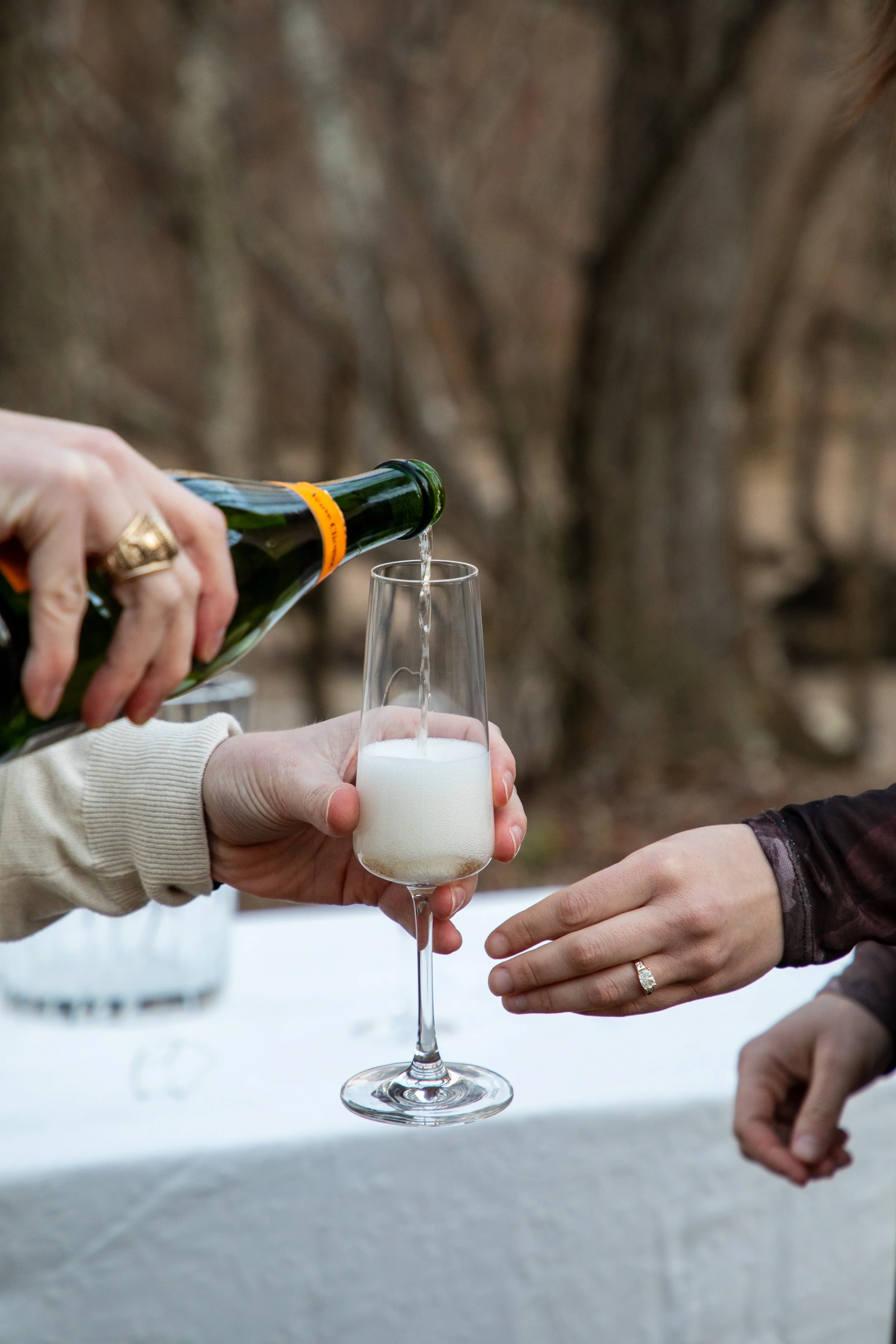 Engagement Photography by Will Locke near Richmond, VA in Montpelier. A glass of champagne is being poured, with a table and a bottle of champagne in the background.