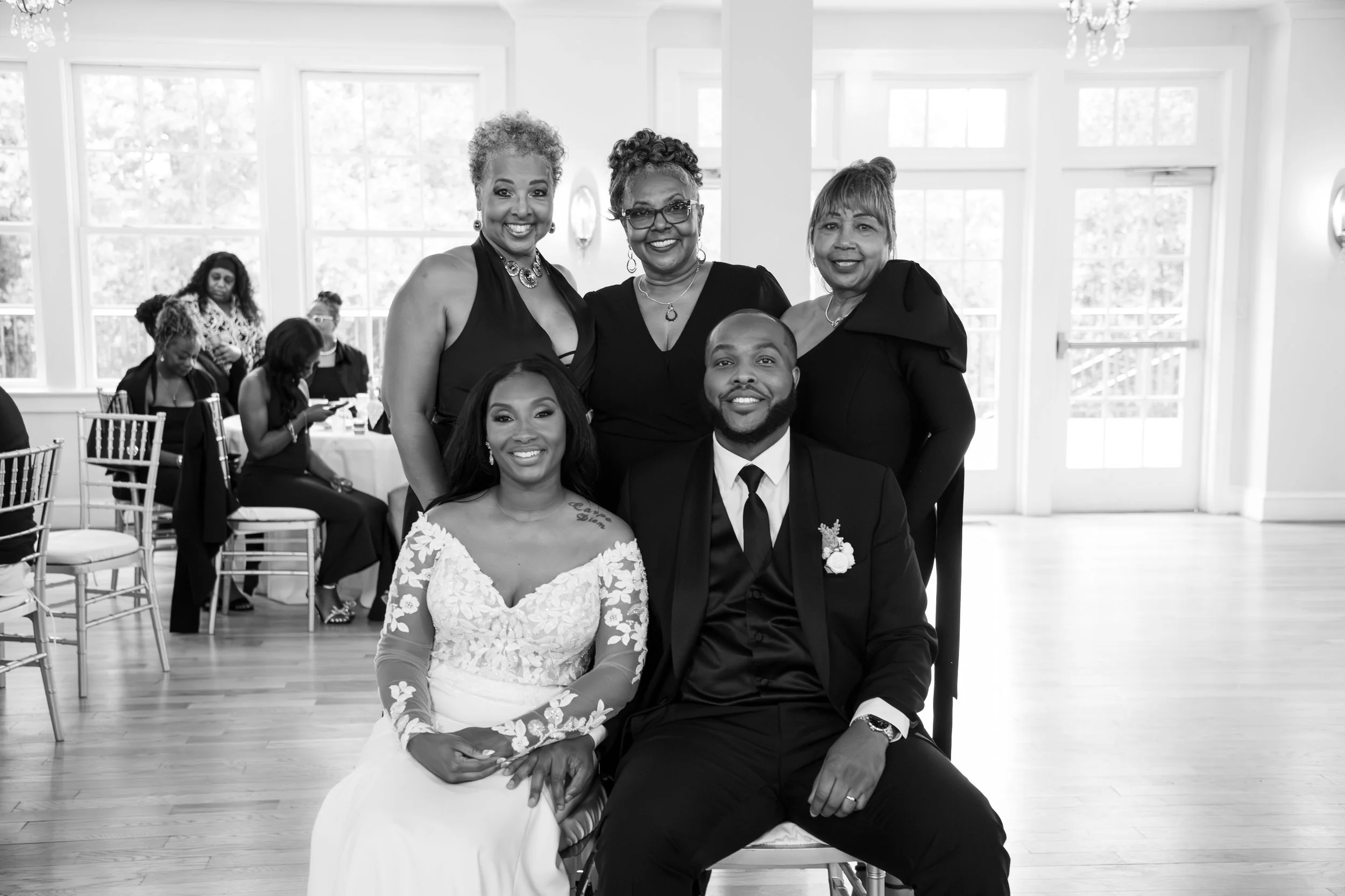 Photo & Video by Will Locke Wedding Photography at the Woman's Club of Portsmouth in Virginia. Group of six well-dressed people, including a bride and groom, posing indoors during a celebration or wedding reception.