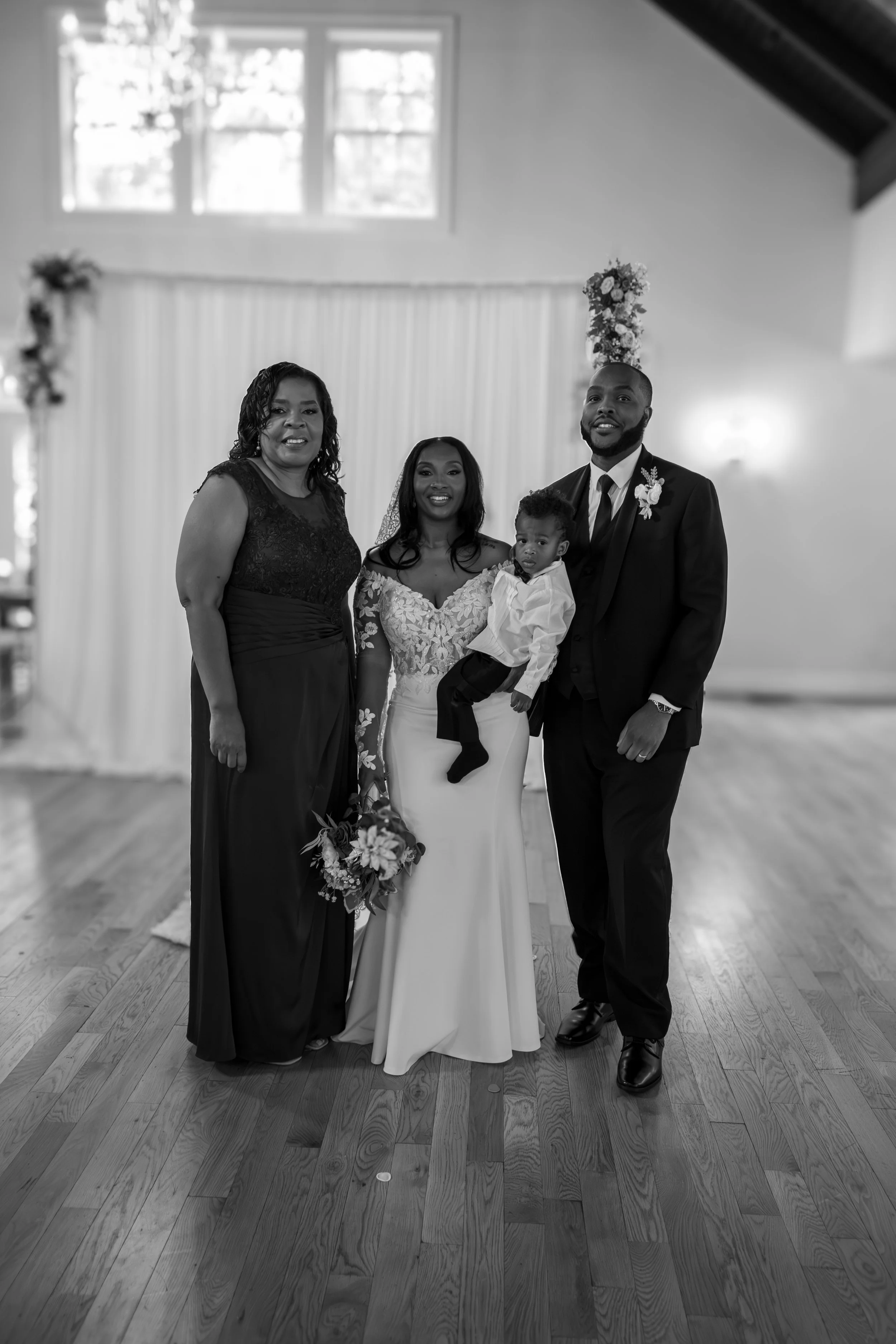 Photo & Video by Will Locke Wedding Photography at the Woman's Club of Portsmouth in Virginia. Black and white photo of a wedding ceremony with four people, including a bride in a gown, inside a decorated venue.