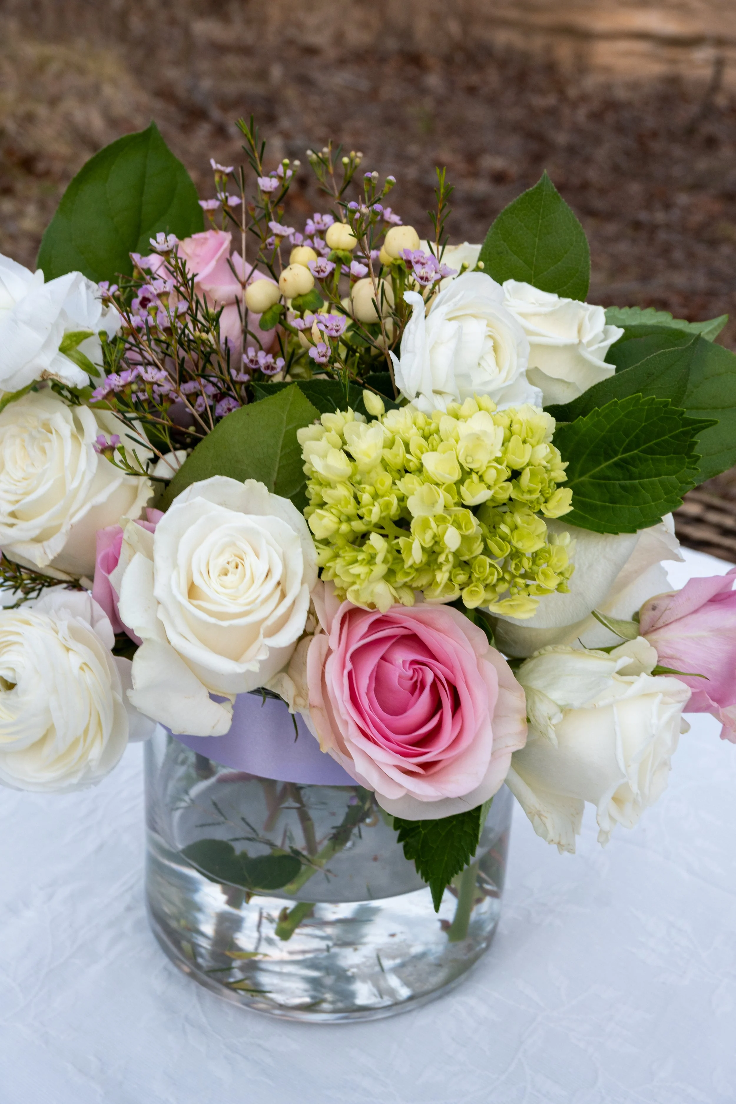 Engagement Photography by Will Locke near Richmond, VA in Montpelier. A flower arrangement sits on a white tablecloth outdoors in the winter with grass behind.