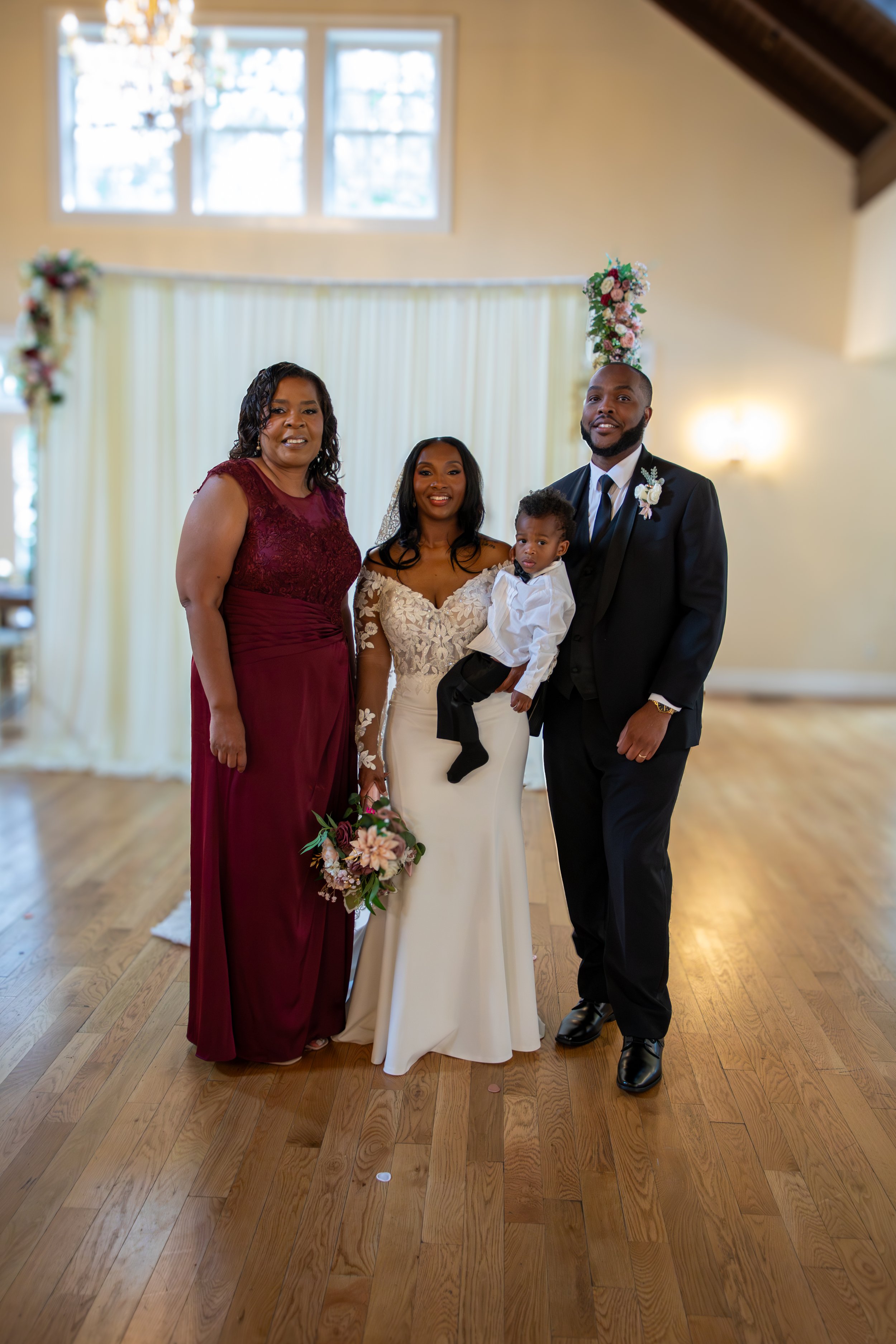 Photo & Video by Will Locke Wedding Photography at the Woman's Club of Portsmouth in Virginia. A group of four people standing in a room with wooden floors, a cream-colored wall, and floral decorations.