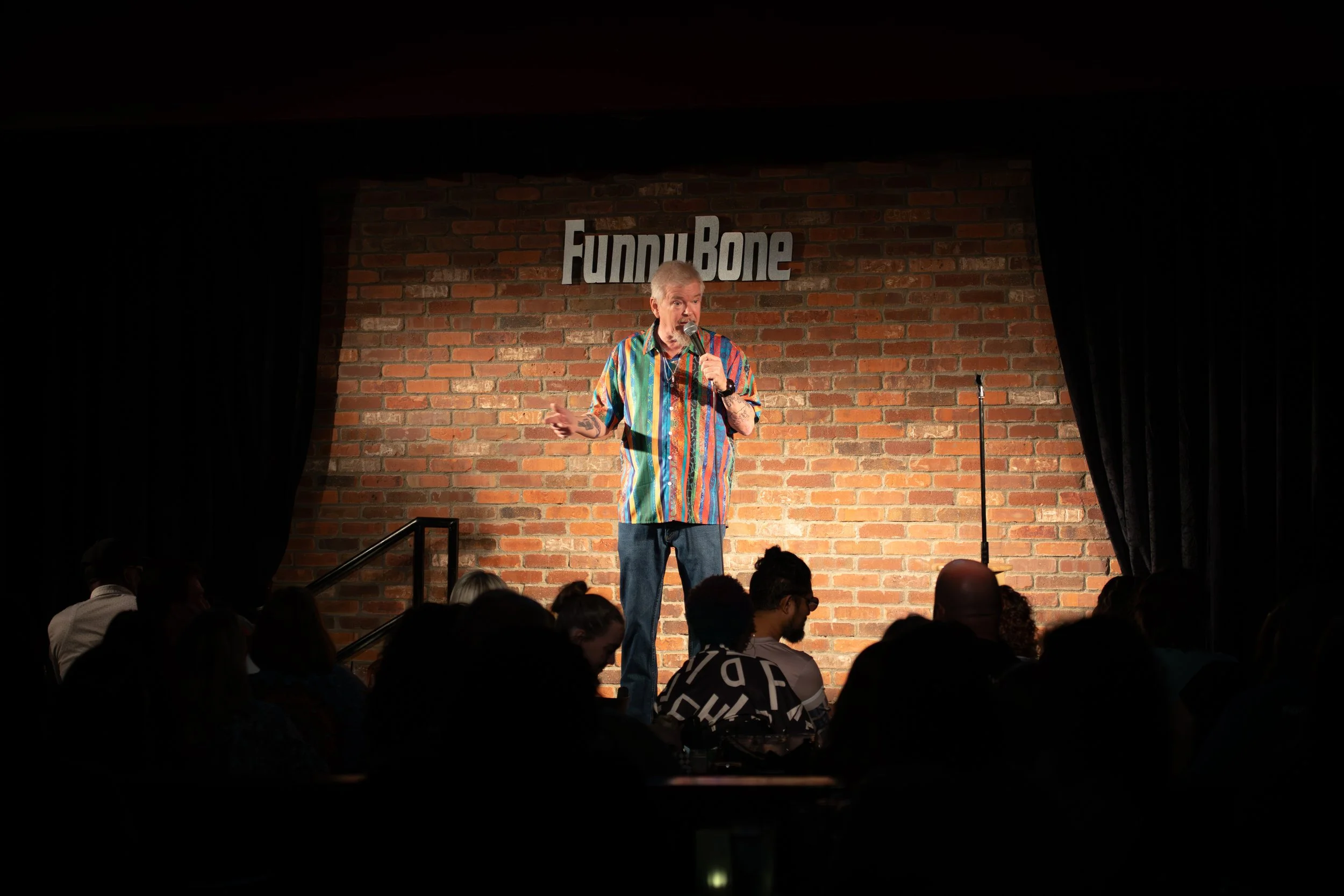 Comedy Photography by Will Locke in Norfolk, VA. Wideshot of comedian speaking on stage with hand out at hip level. 