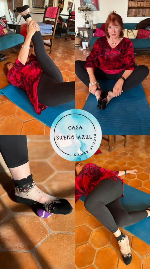 Woman practicing yoga indoors, sitting cross-legged on a blue yoga mat, with close-up of her foot on a purple yoga block and stretching on the mat.