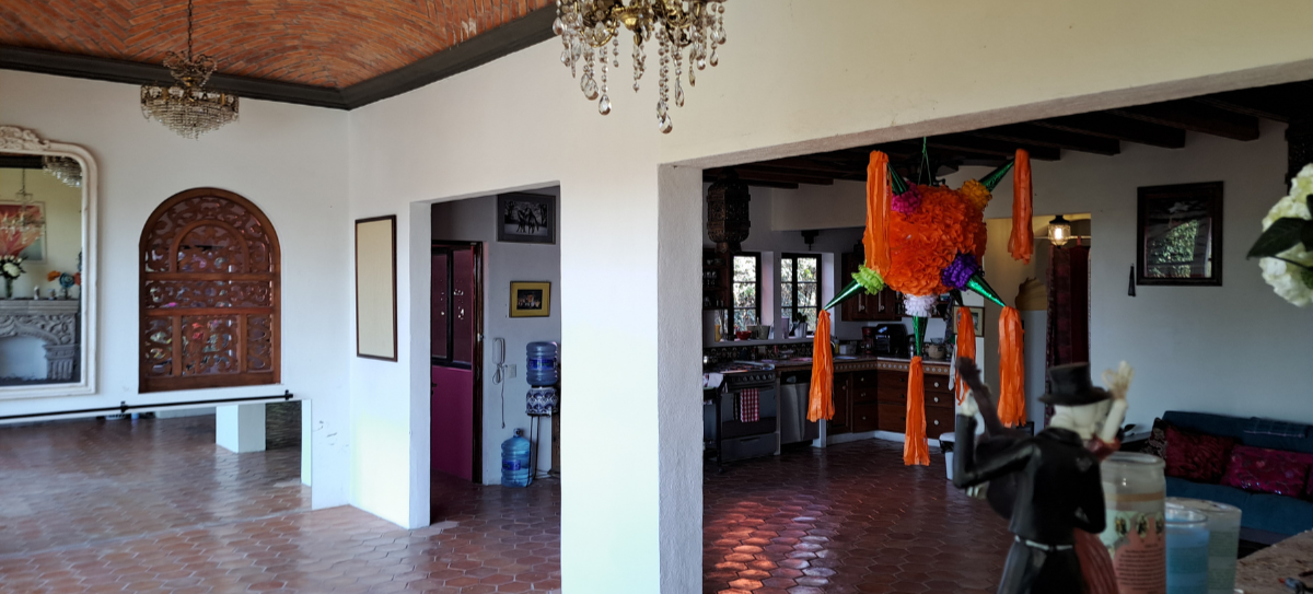 Interior of a house with brick floor and ceiling, chandelier, kitchen in the background, and a colorful piñata hanging from the ceiling.