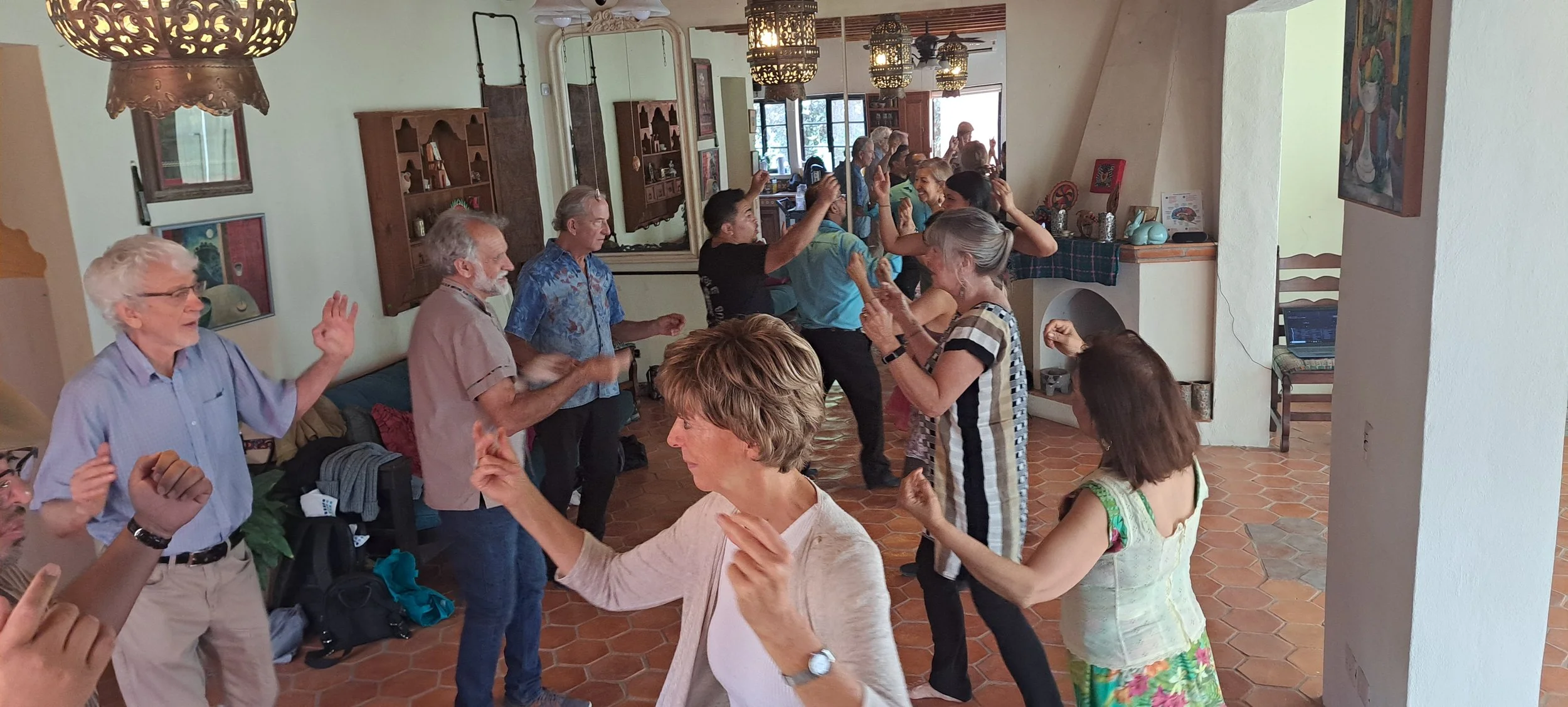 Group of people dancing and having fun in a cozy indoor space with warm lighting and decorative hanging lamps.