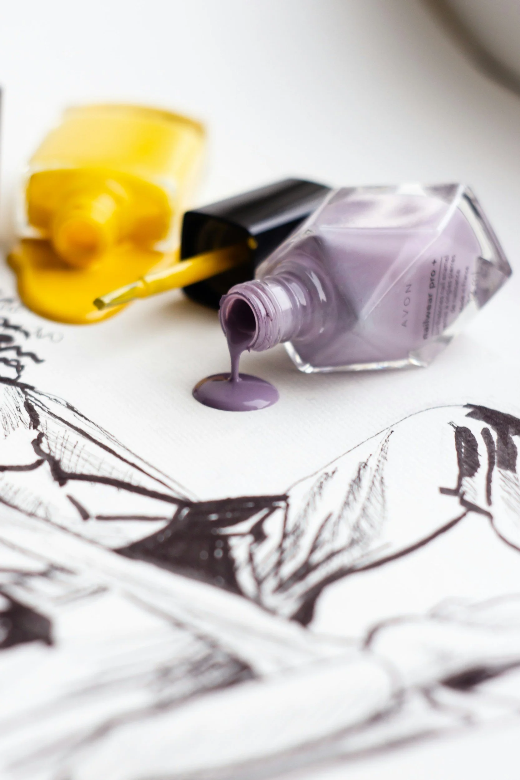 two bottles of spilled nailpolish - one is yellow and one is purple