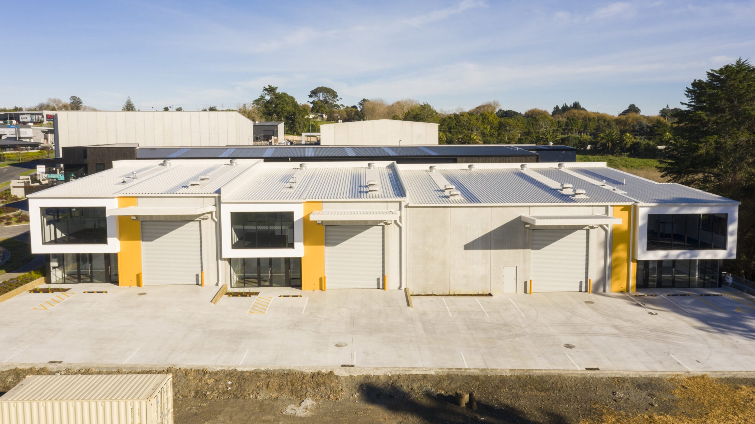 View across at shared concrete parking and driveway to Best Nest Building Co multi unit Commercial New Build where Swift Roofing installed a 910mm Maxispan Roof and 300mm in ColorCote's Titania coloured ZinaCore coating. Image c/o Best Nest Building