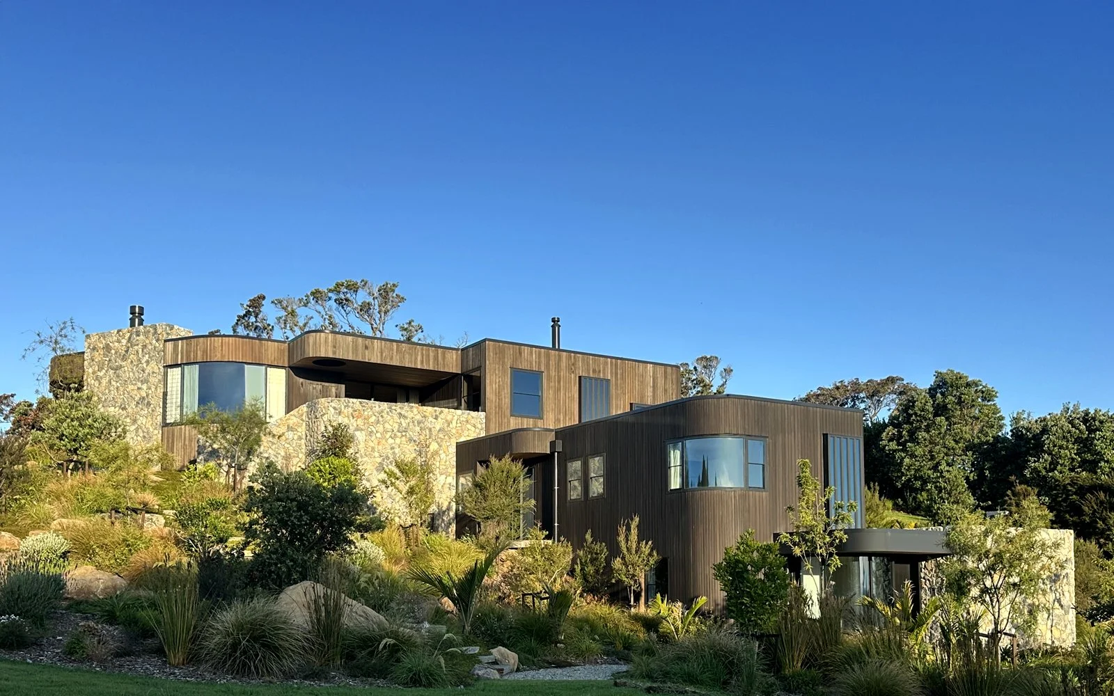 Curved parapet capping and window flashings visible around roof of Ti Point House, a Lindesay / Construction Crosson Architects / Rochford Landscapes project where Swift Roofing installed RT7 Roof in ColorCote Horoeka coloured MagnaFlow from Roofing 