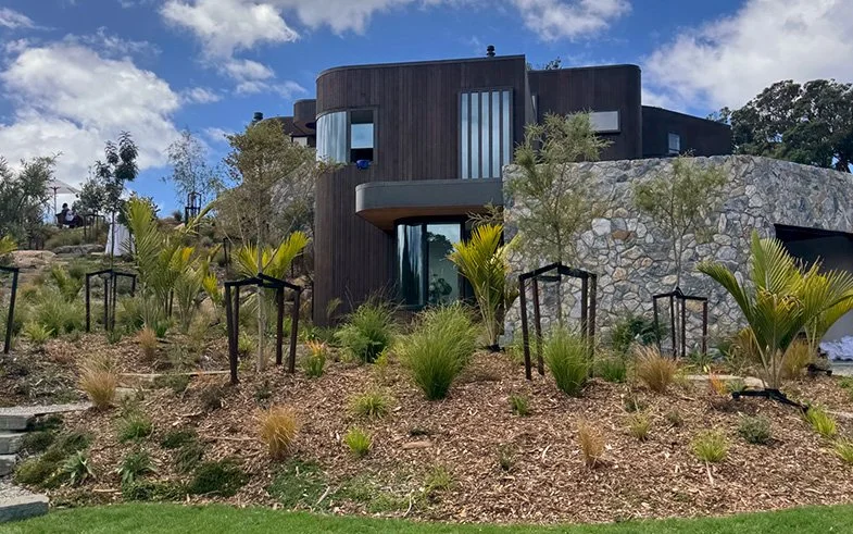 Curved parapet capping and window flashings mixed with stone work around roof of Ti Point House, a Lindesay / Construction Crosson Architects / Rochford Landscapes project where Swift Roofing installed RT7 Roof in ColorCote Horoeka coloured MagnaFlow