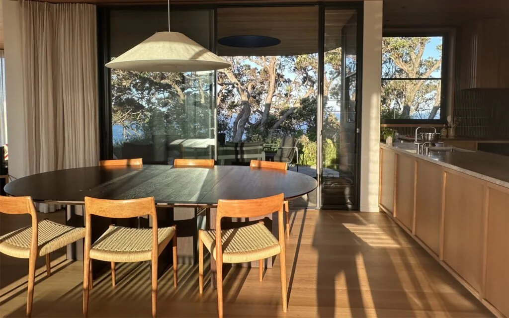Dining table at Ti Point House, a Lindesay / Construction Crosson Architects / Rochford Landscapes project where Swift Roofing installed RT7 Roof in ColorCote Horoeka coloured MagnaFlow from Roofing Industries. Photo Crosson Architects