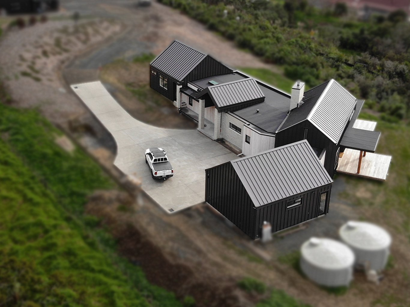 Pulled back view looking north west over partially completed Wenderholm new build with Swift Roofing installed ColorCote ZinaCore Ironsand coloured Eurostyle Spanlok 365 New Build Roofing, Wall Cladding and Parapet Capping.