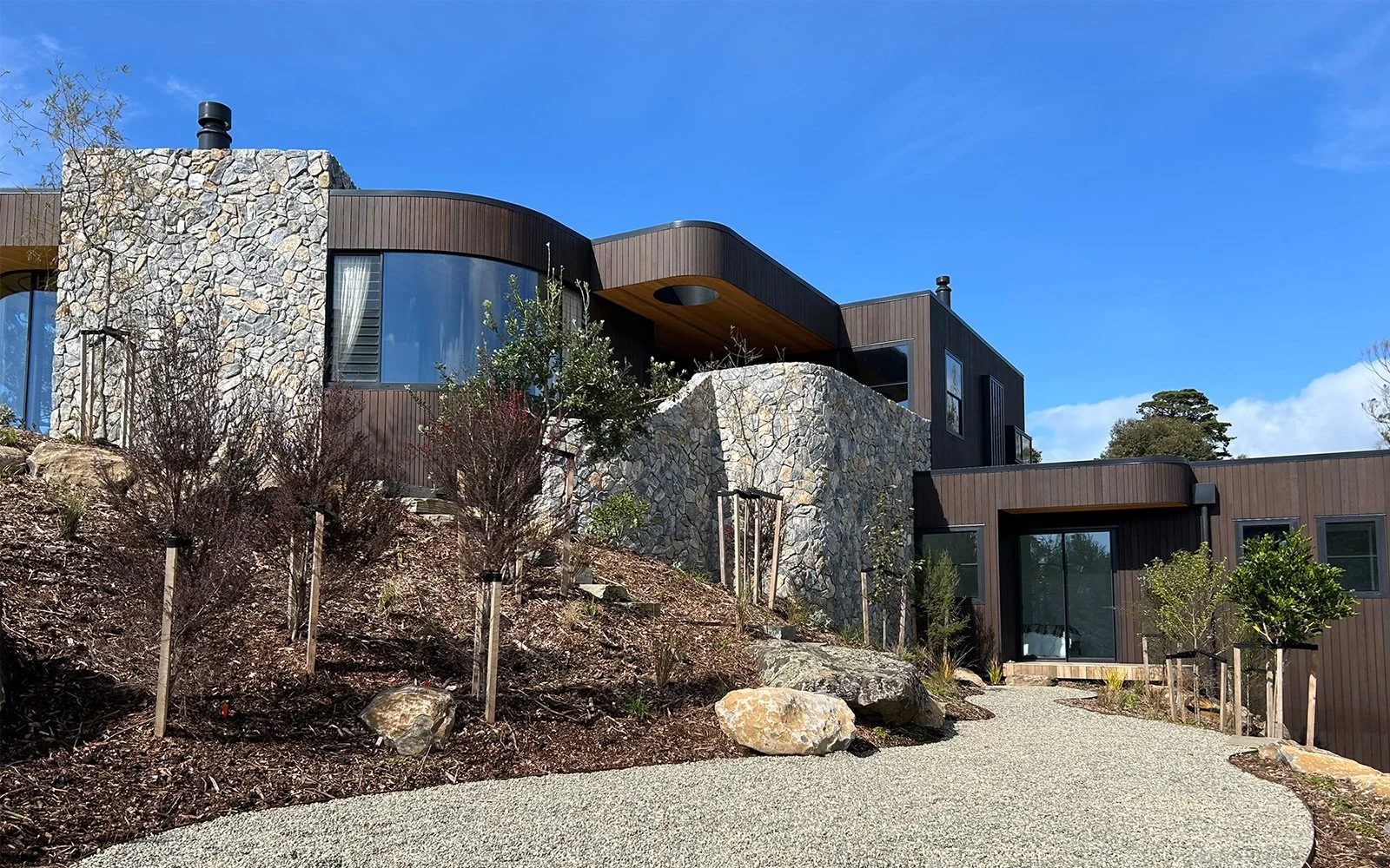 Curved parapet capping and window flashings visible around roof of Ti Point House, a Lindesay / Construction Crosson Architects / Rochford Landscapes project where Swift Roofing installed RT7 Roof in ColorCote Horoeka coloured MagnaFlow from Roofing 
