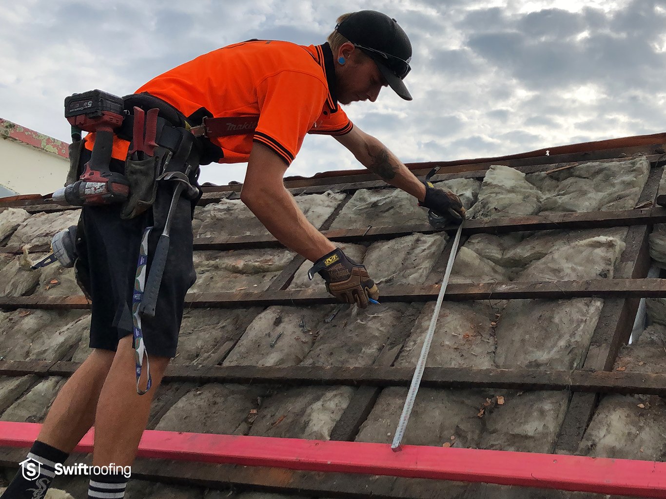 View of Swift Roofing installer measuring for new Trimrib profile roofing on front roof area.