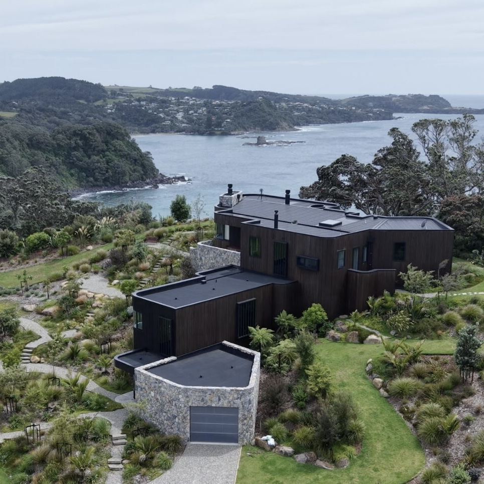 Drone view over Ti Point House showing Rochford Landscapes / Lindesay Construction / Crosson Architects project where Swift Roofing installed RT7 Roof in ColorCote Horoeka coloured MagnaFlow from Roofing Industries