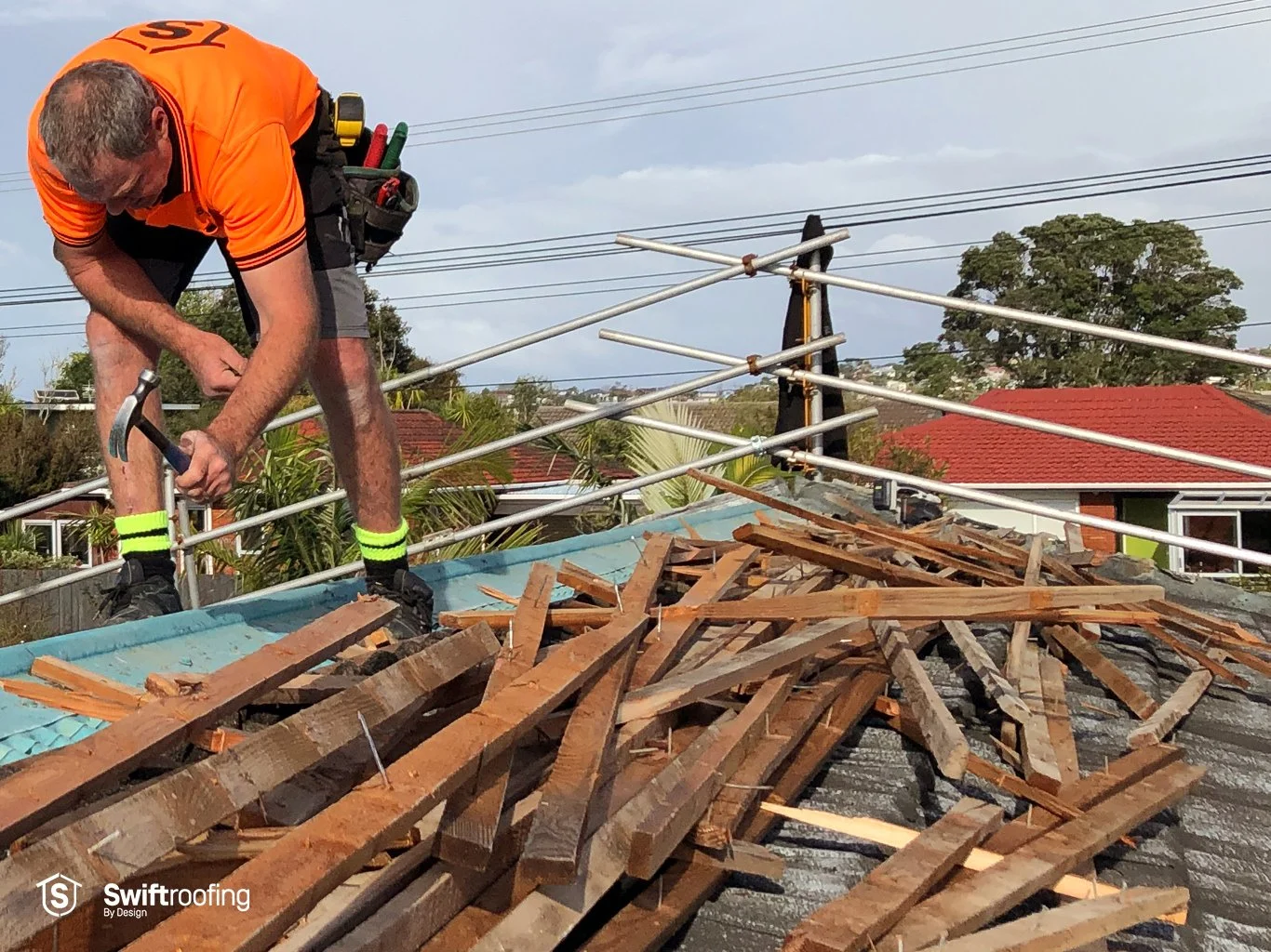 Swift Roofing installer removing double layer of old roof tiles on top of underlying old metal roof on double strip roof replacement where Swift Roofing installed the new Corrugate & Trimrib roofs in Torbay.