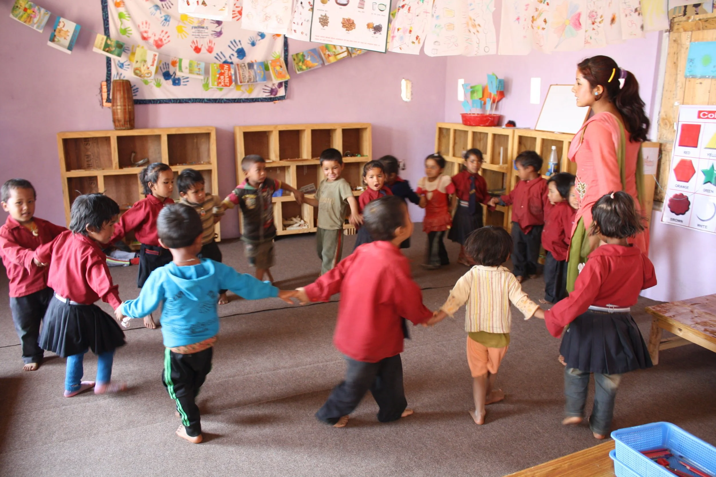 Image c/o First Steps Himalaya of local Nepalese children dancing in a classroom built by Court Construction.
