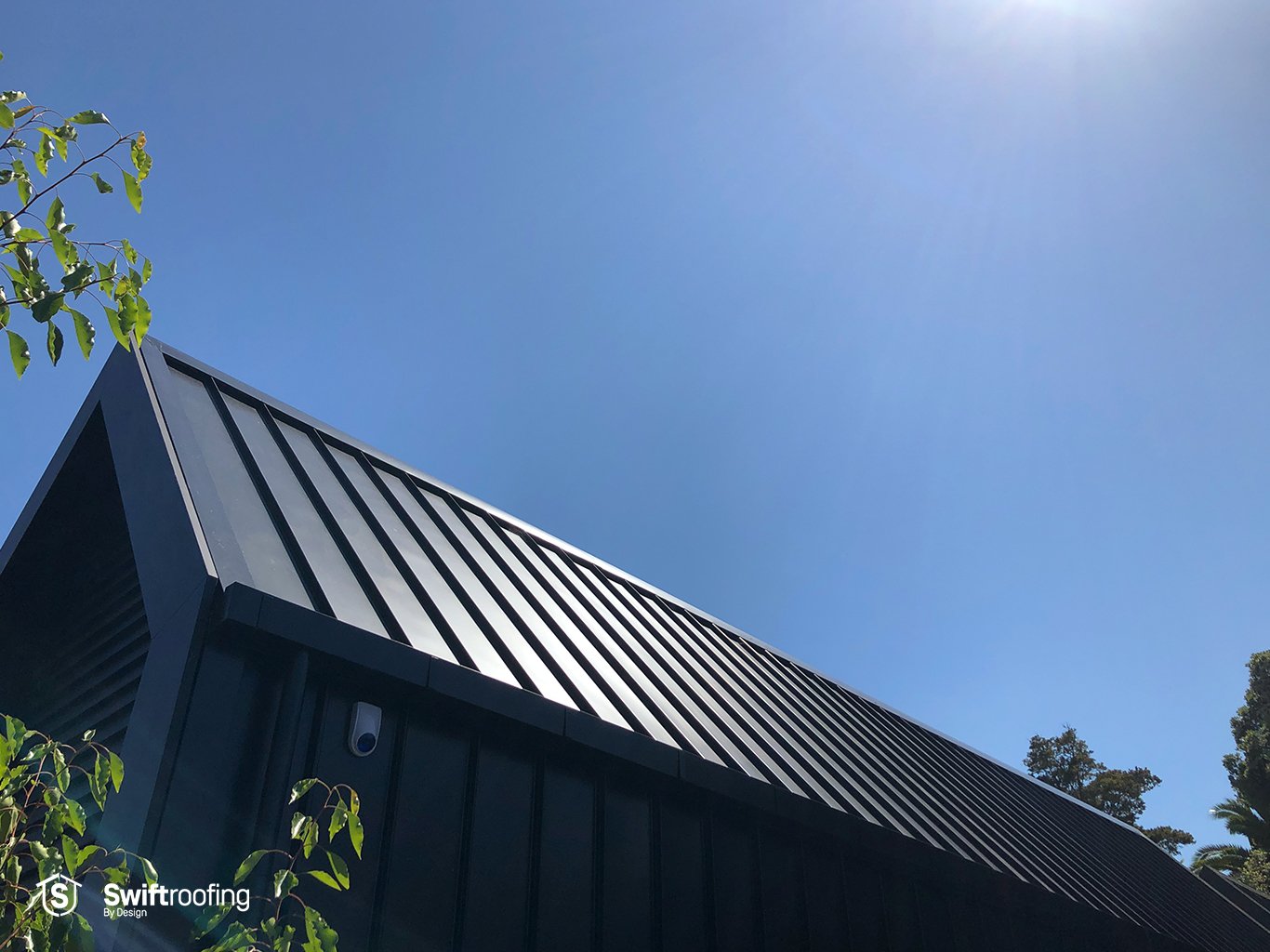 Ground view up towards black front roof of House of the Year Regional Gold and Top 100 winning Ninety45 New Build, in Remuera, where Swift Roofing installed Eurostyle Spanlok 365 Roofing and Wall Cladding in Black and White.