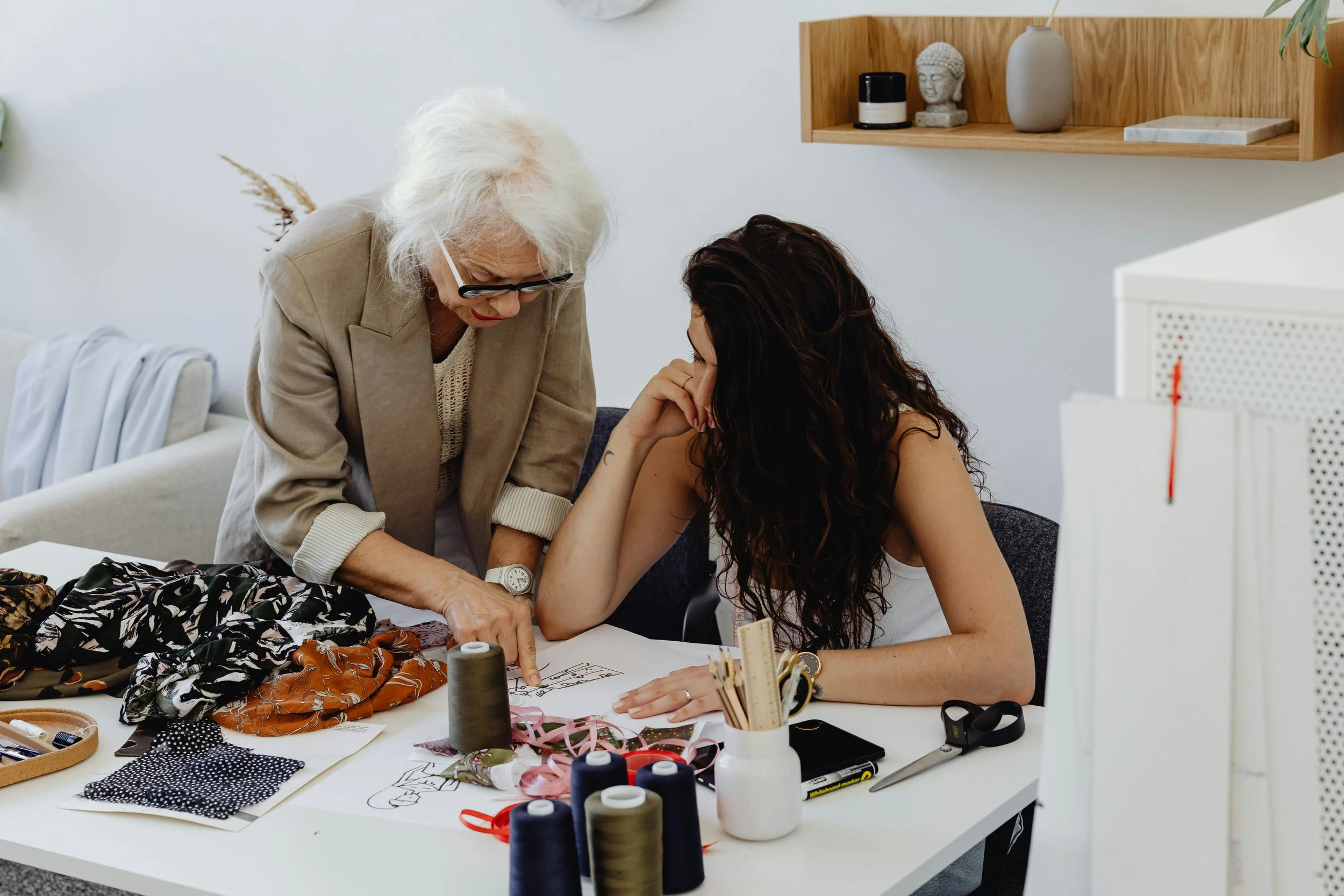 Experienced female fashion designer mentoring a young woman