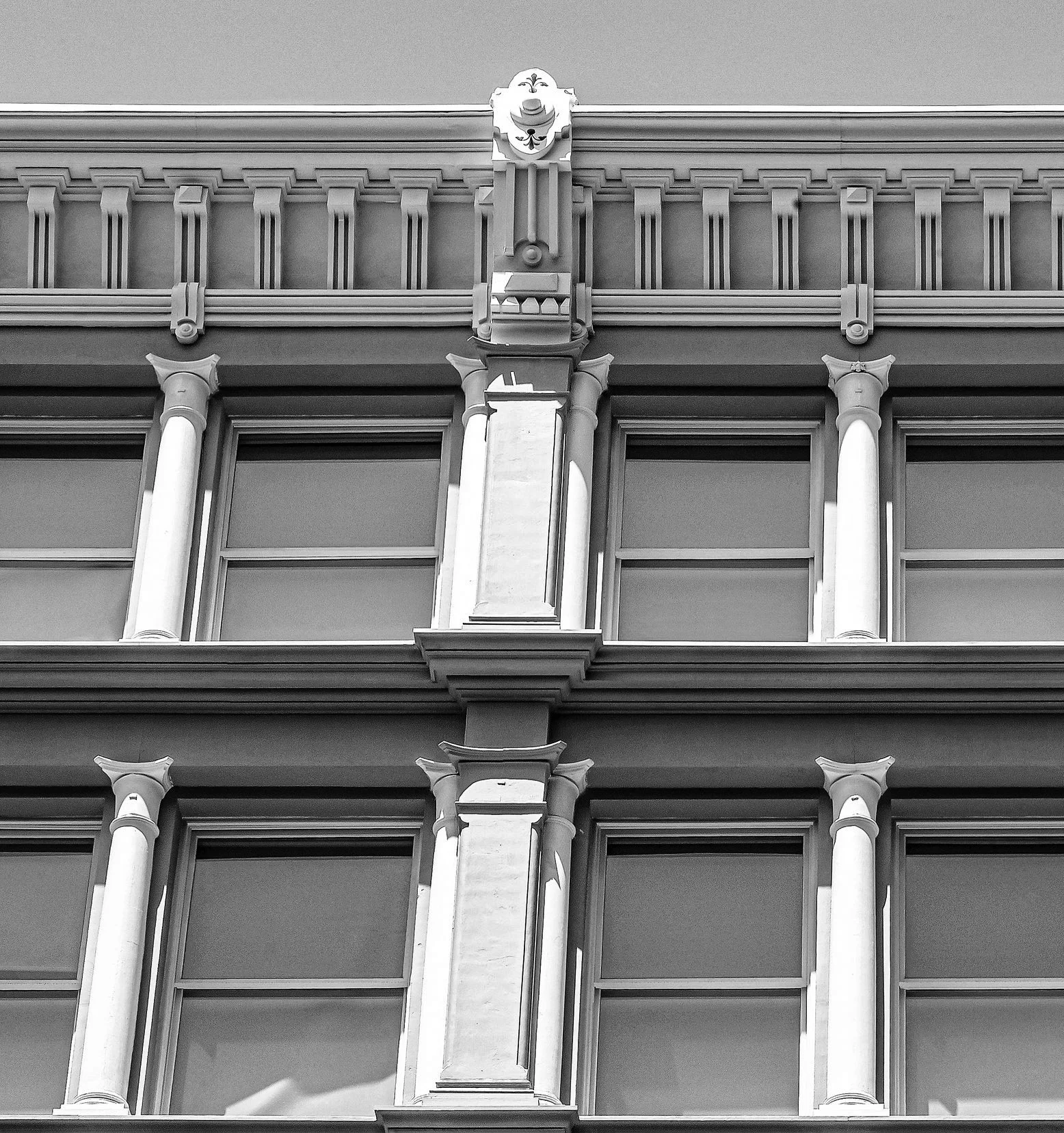 Close-up of a historic building facade with decorative columns, ornate moldings, and a sculpted face at the top center, in black and white.