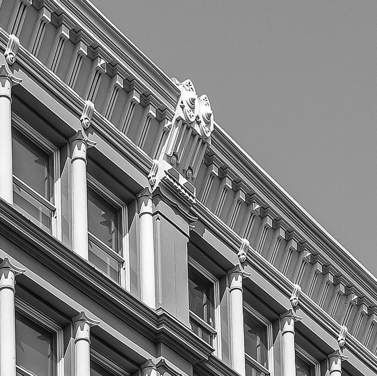 Close-up of an ornate building facade with decorative architectural details and smiling face sculptures, black and white photo.