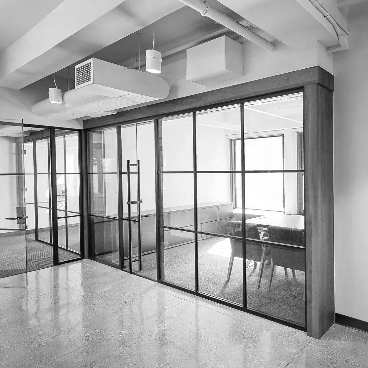 Modern office with glass-walled conference room, chairs, and window.