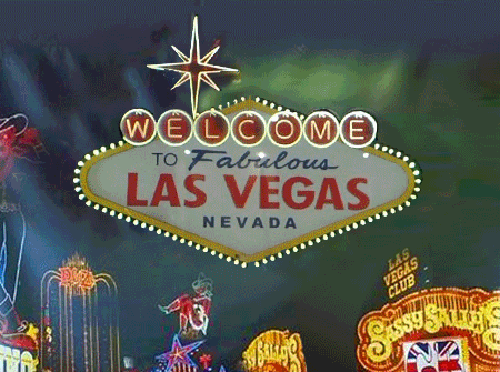 Las Vegas welcome sign illuminated at night with neon lights and signs.
