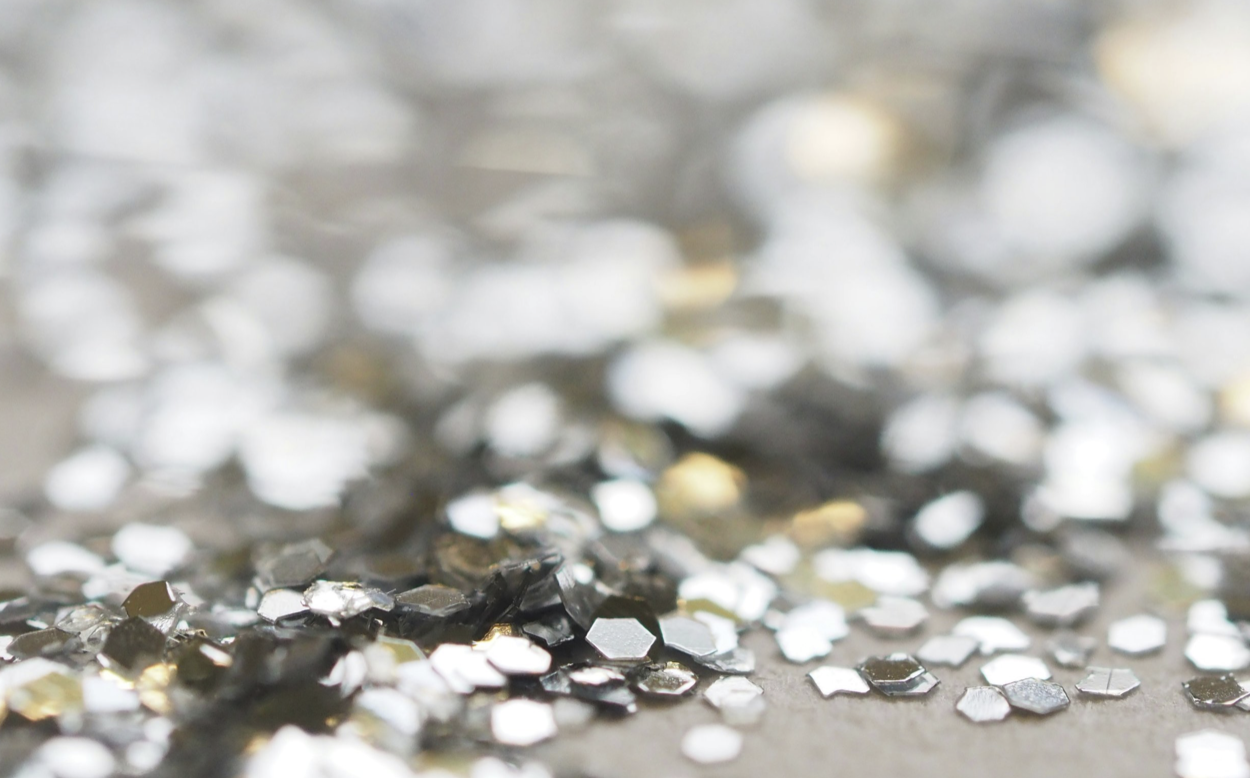 Close-up of silver, hexagon-shaped glitter scattered on a surface.