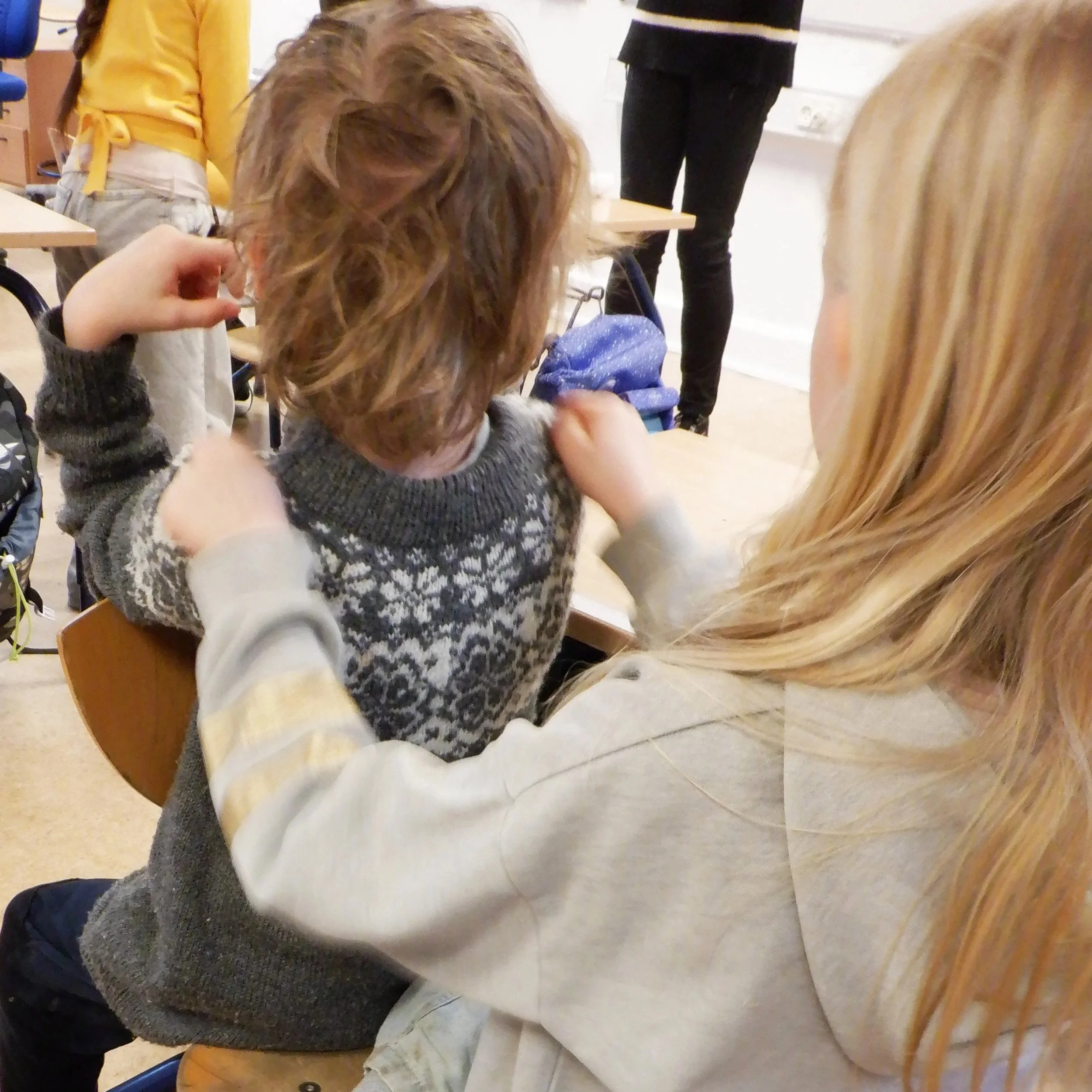 En voksen hjælper en barn med at tage på en skolearmbånd.