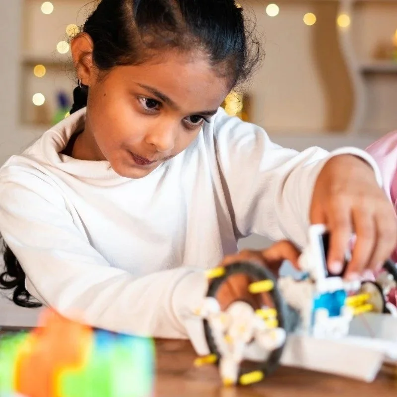En ung pige leger med en kompleks LEGO-model på et bord