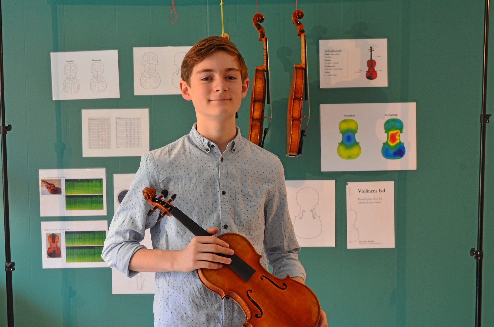 Ung mand fra Skt. Josefs Skole med violin foran væg med plancher