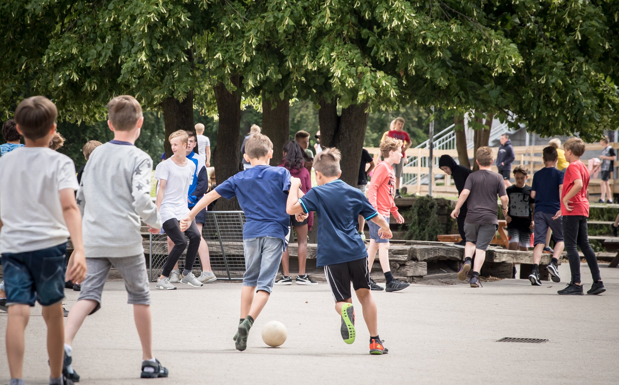 Drenge der spiller fodbold i skolegården