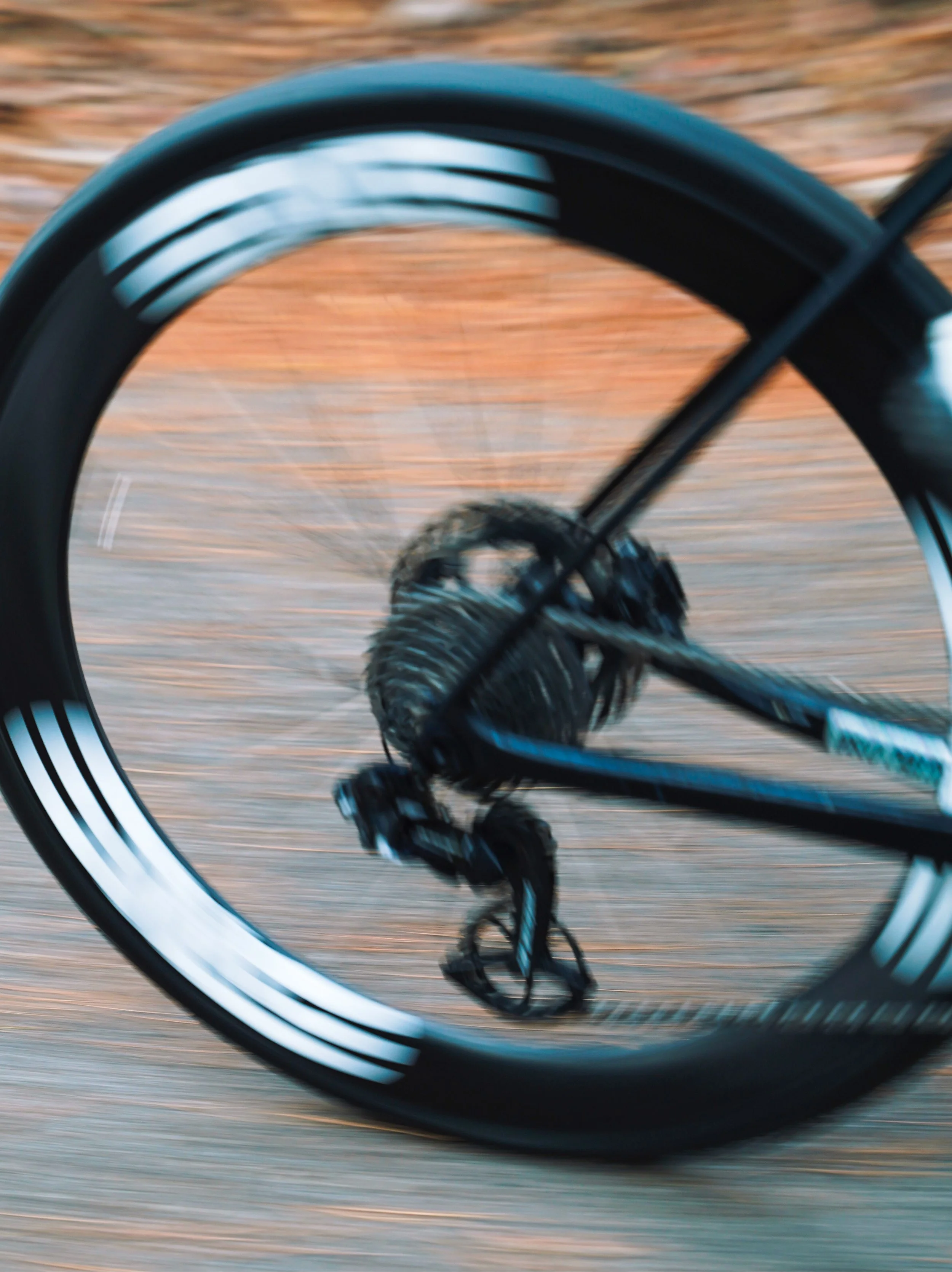 Close-up of a bicycle wheel in motion, with the background and rider slightly blurred.
