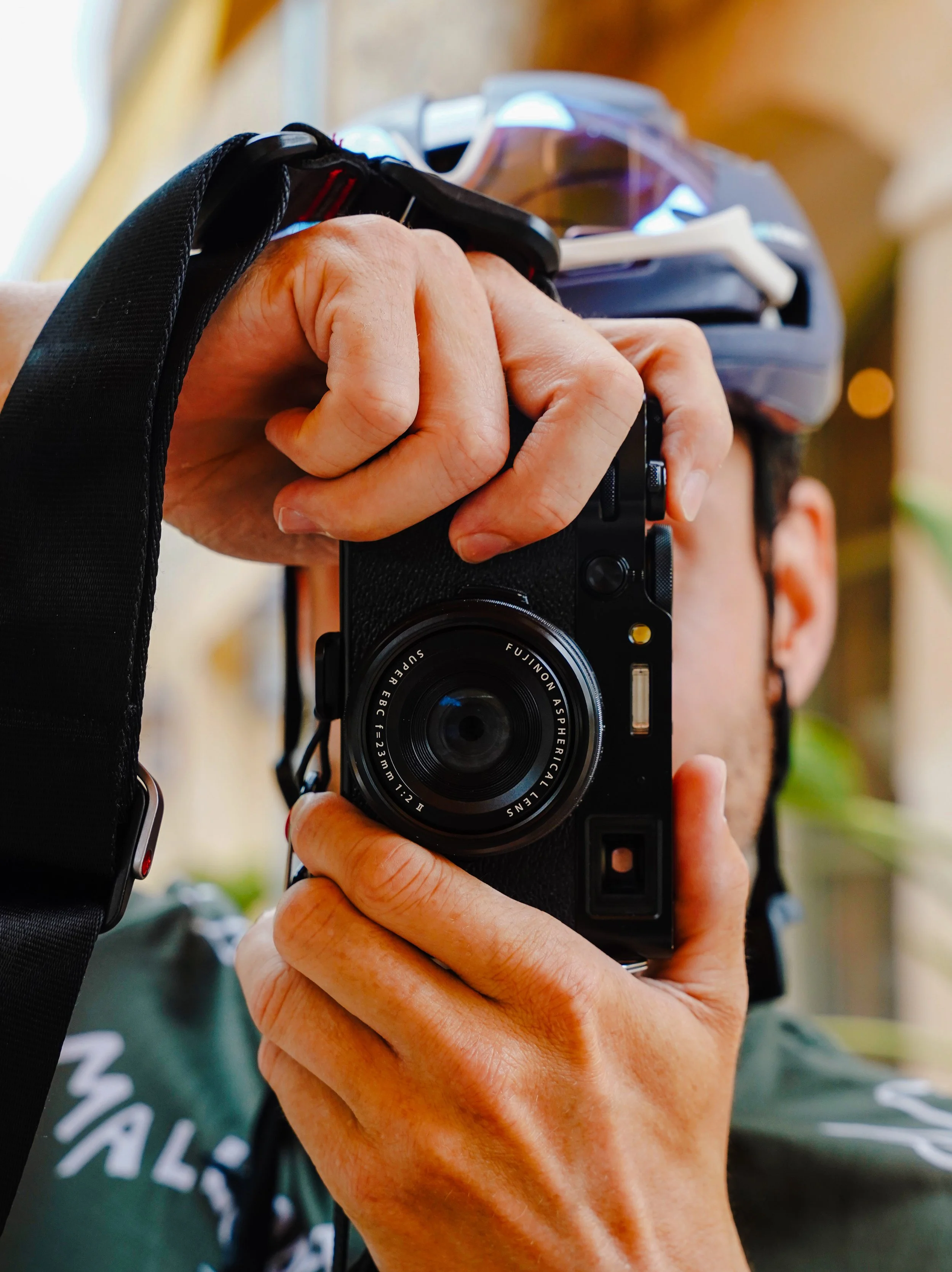 Person holding a camera, wearing a helmet, with a blurred background