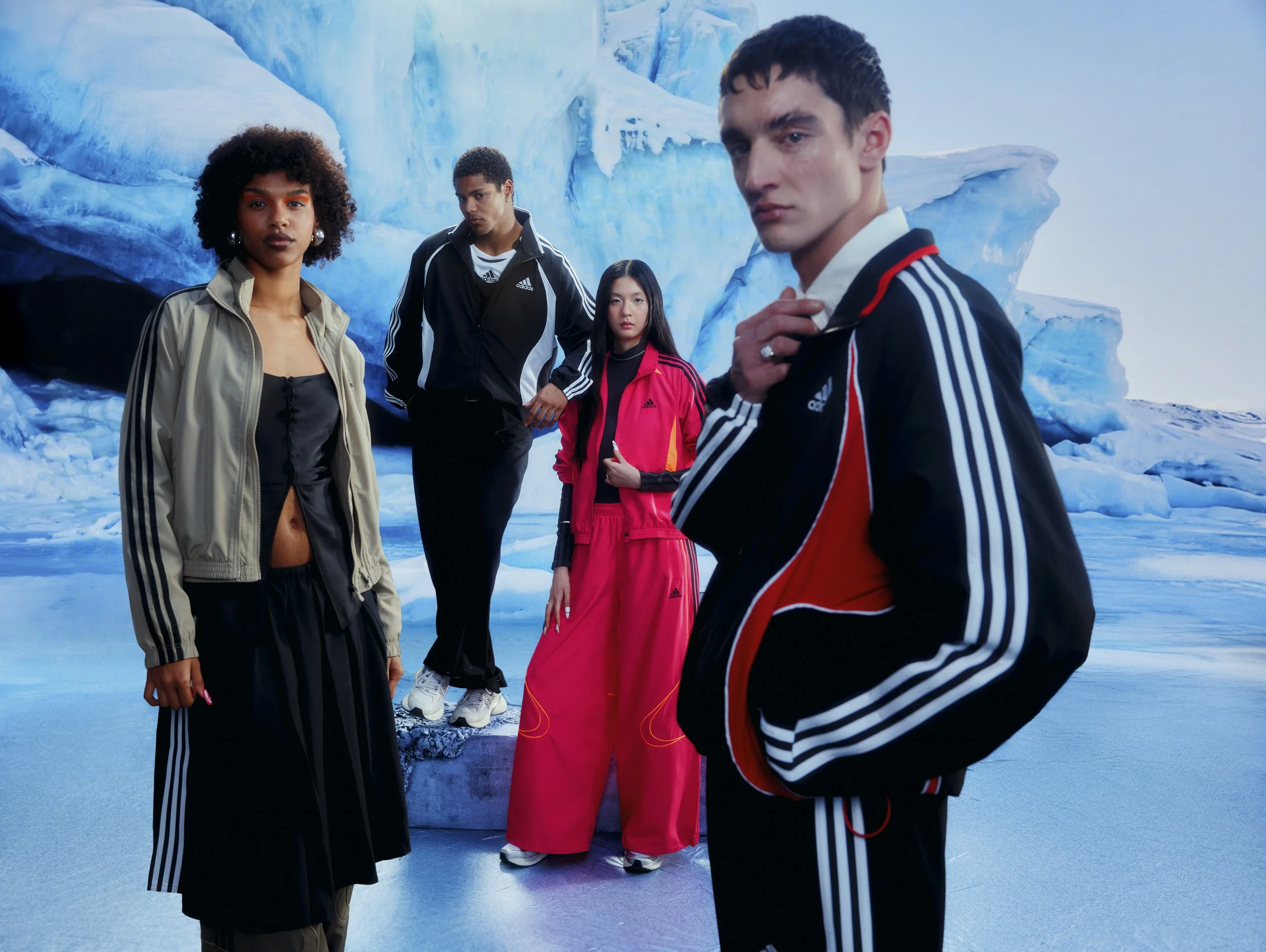 Four diverse young adults in colorful sportswear standing in front of an icy glacier landscape, posing for a photo.
