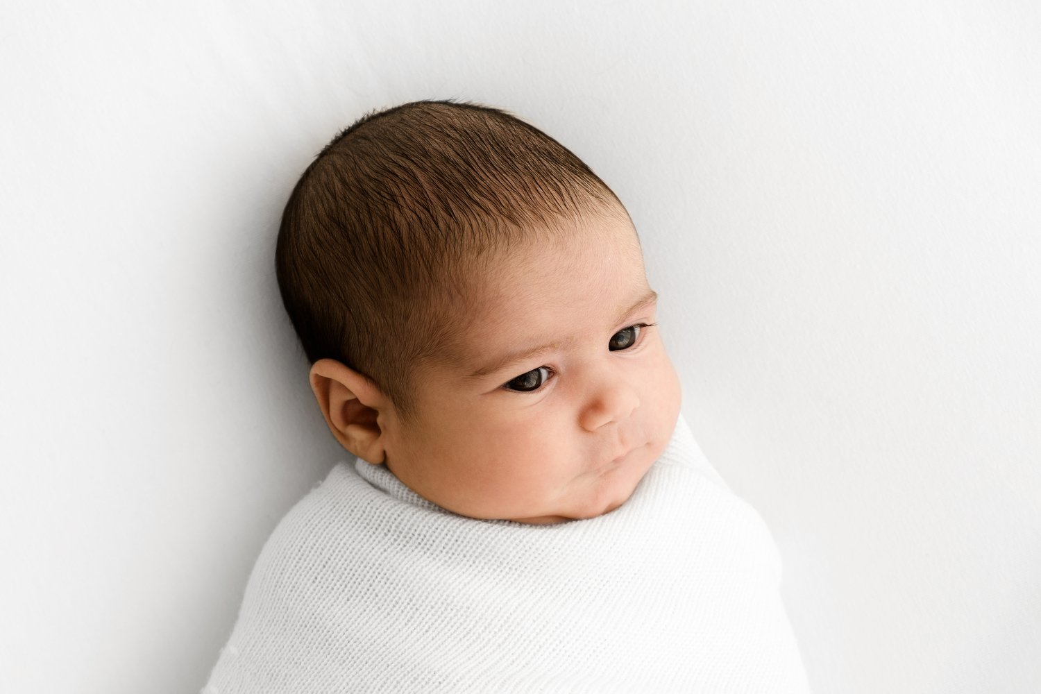 Newborn baby sleeping on a white blanket in soft natural light
