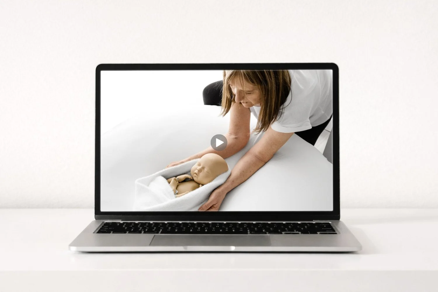 Newborn photography mentor demonstrating wrapping technique with StandInBaby® in minimalist white studio.